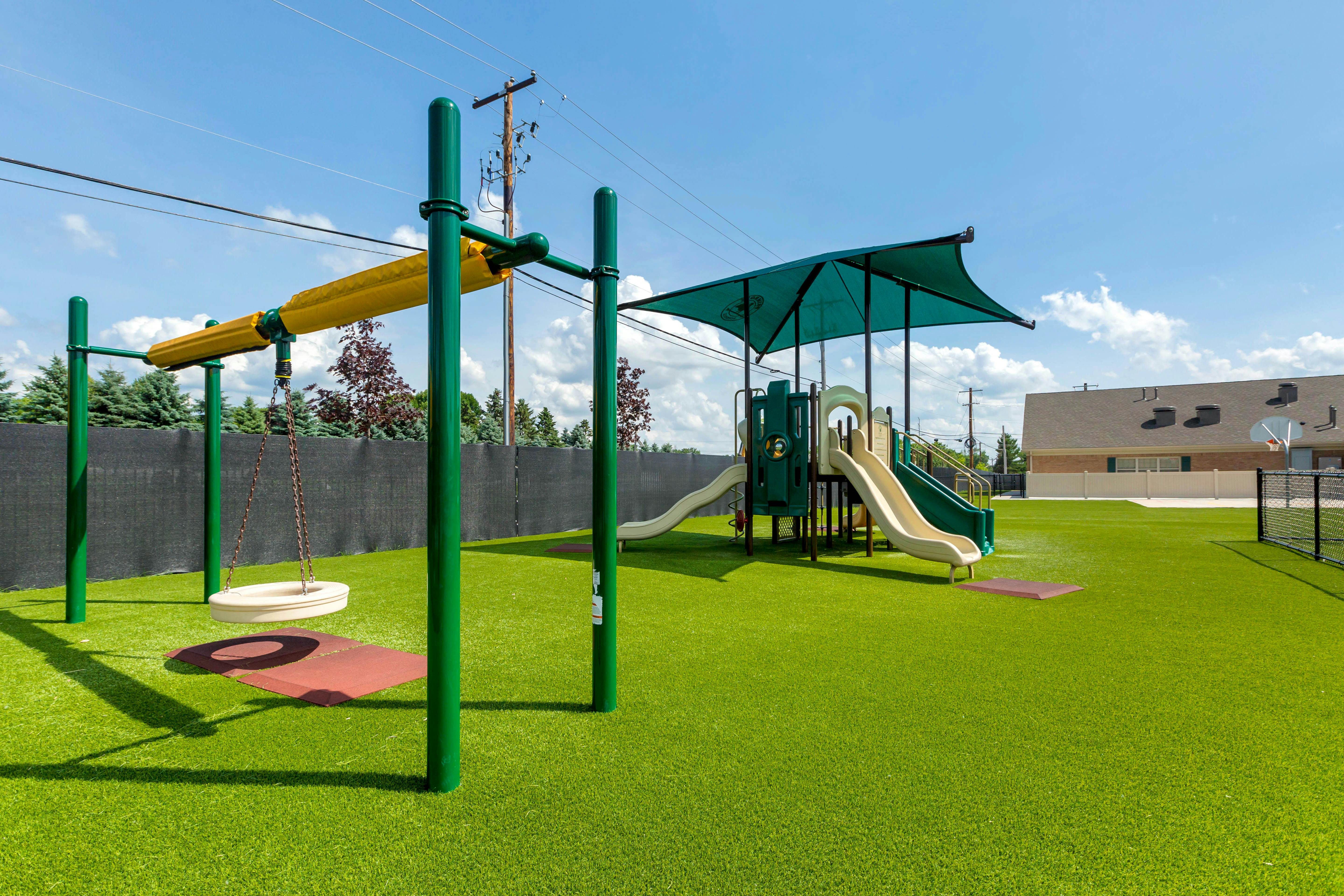 Empty playground with artificial turf, slides, and a swing set