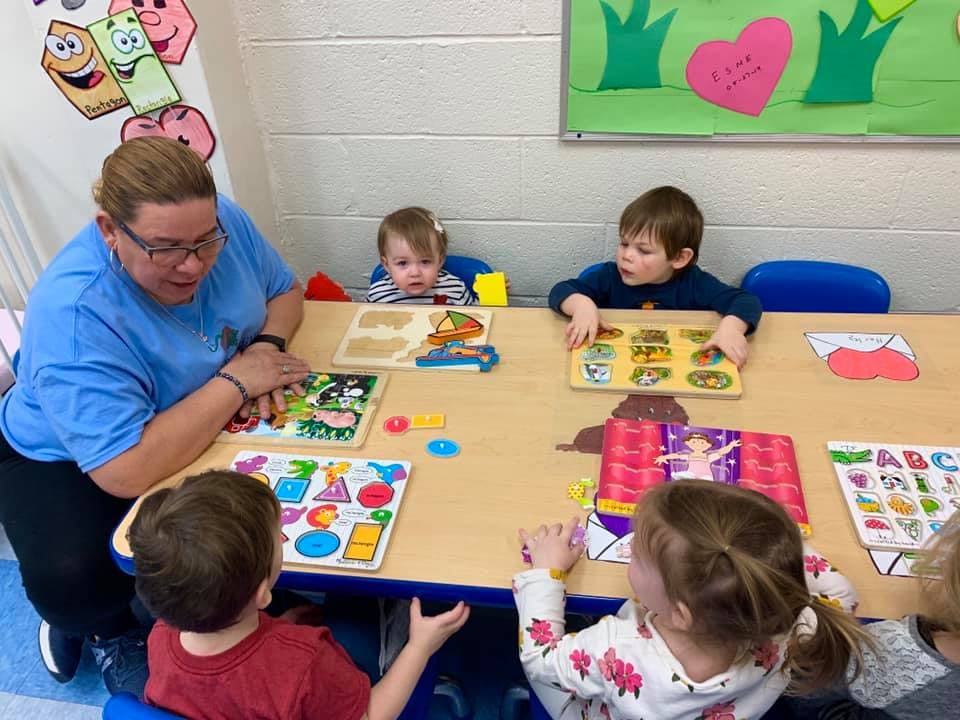 Adult and children at a table playing with puzzles and learning toys