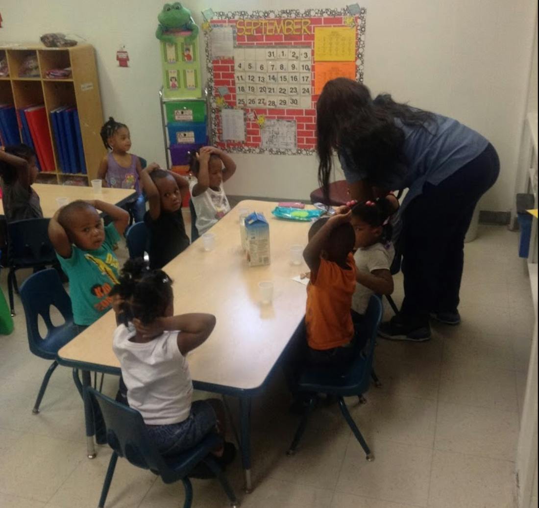 Adult interacting with children at a table in a classroom