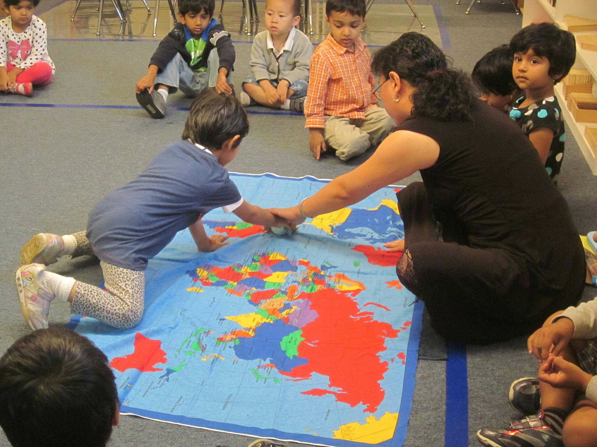 Adult and child interacting with a colorful world map on the floor