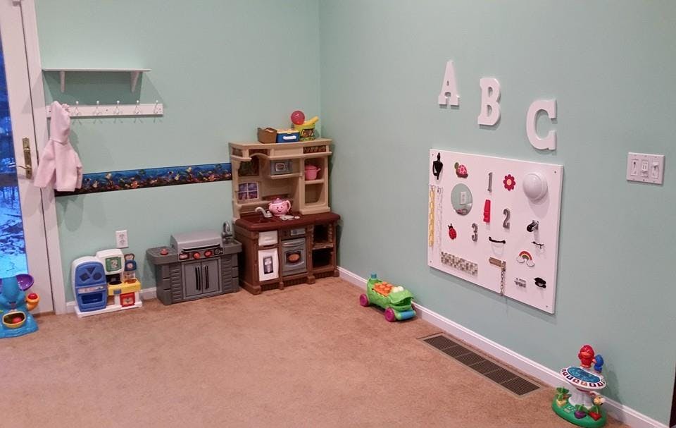 Playroom with toy kitchen, activity board, and ABC letters on wall