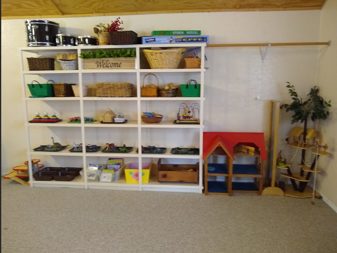 White shelving unit with various items, next to a small playhouse and plant