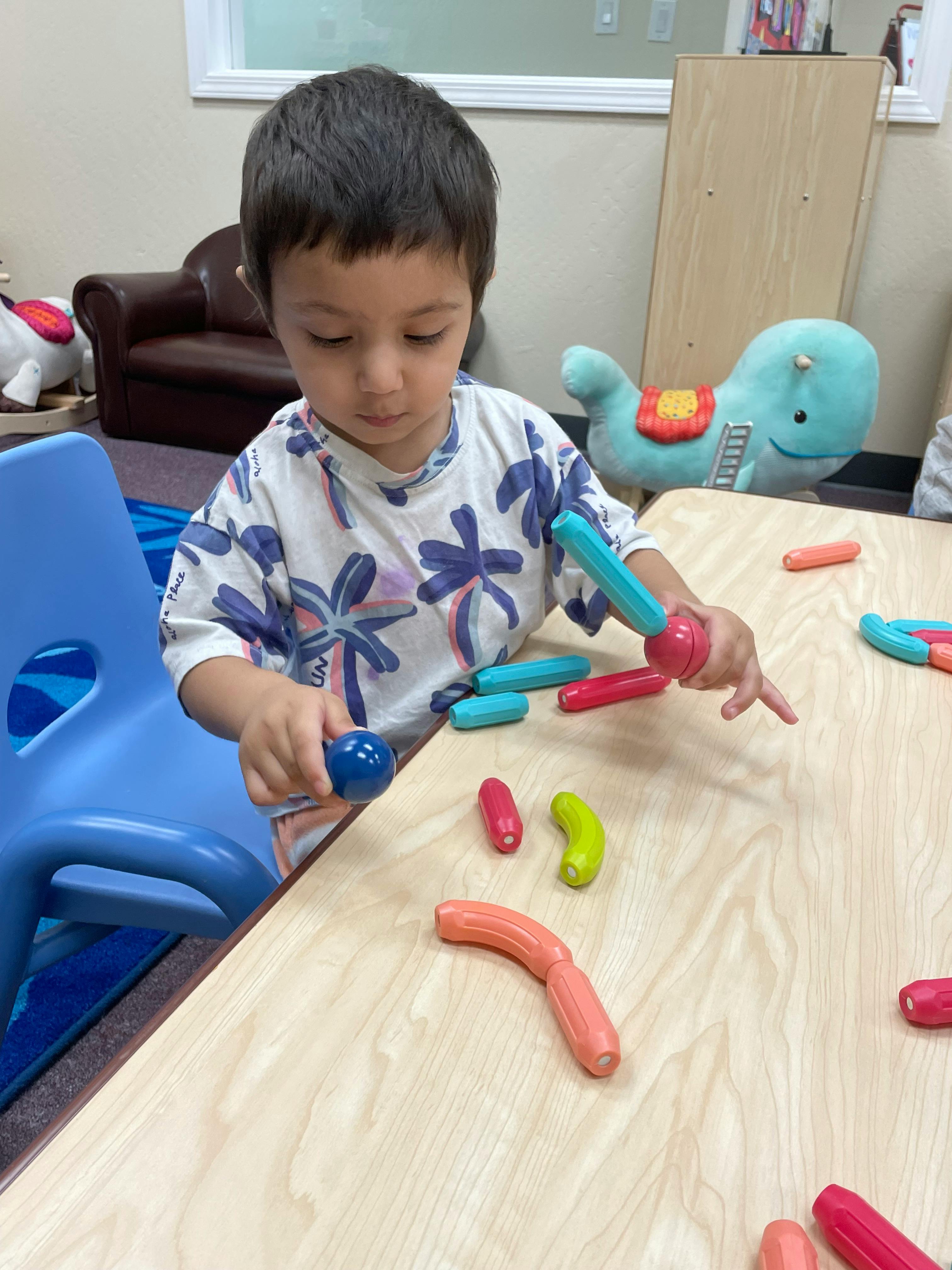 Child playing with colorful magnetic building toys on a table