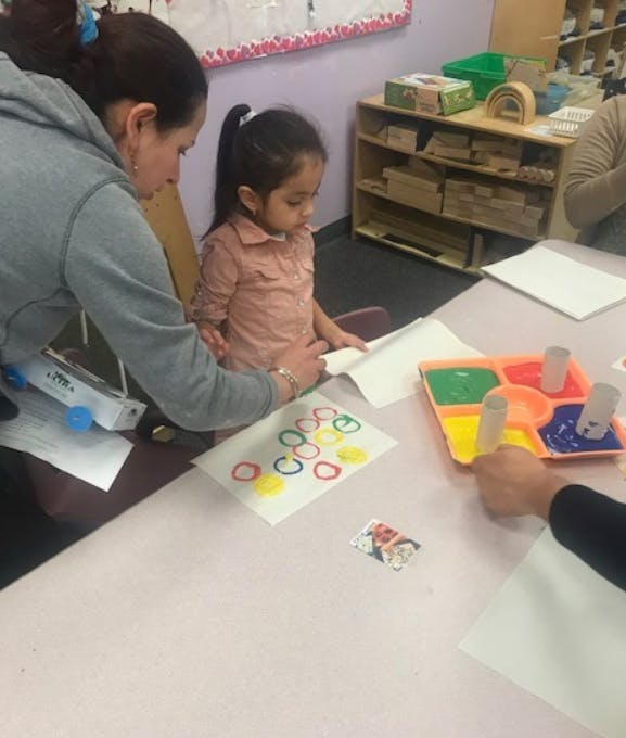 Adult and child painting circles on paper at a table