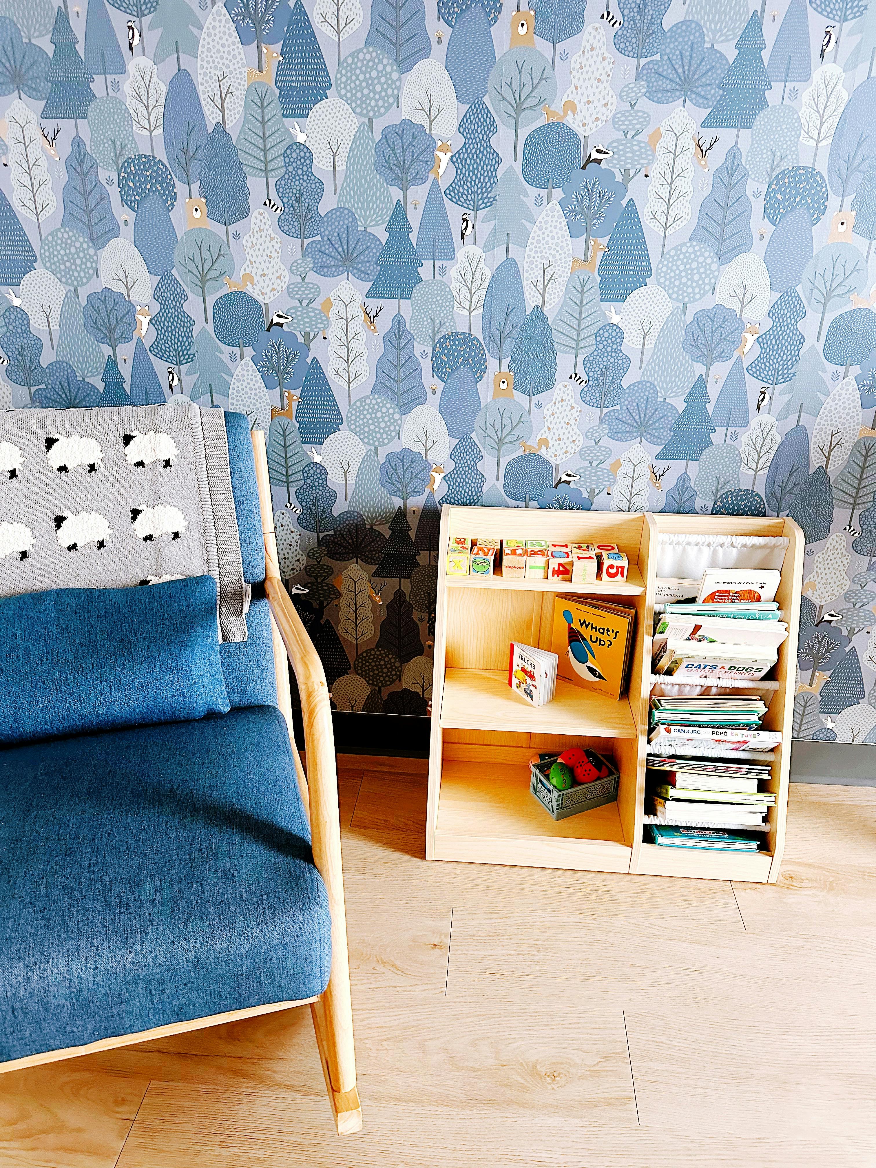Blue armchair with a sheep blanket next to a wooden bookshelf with children's books