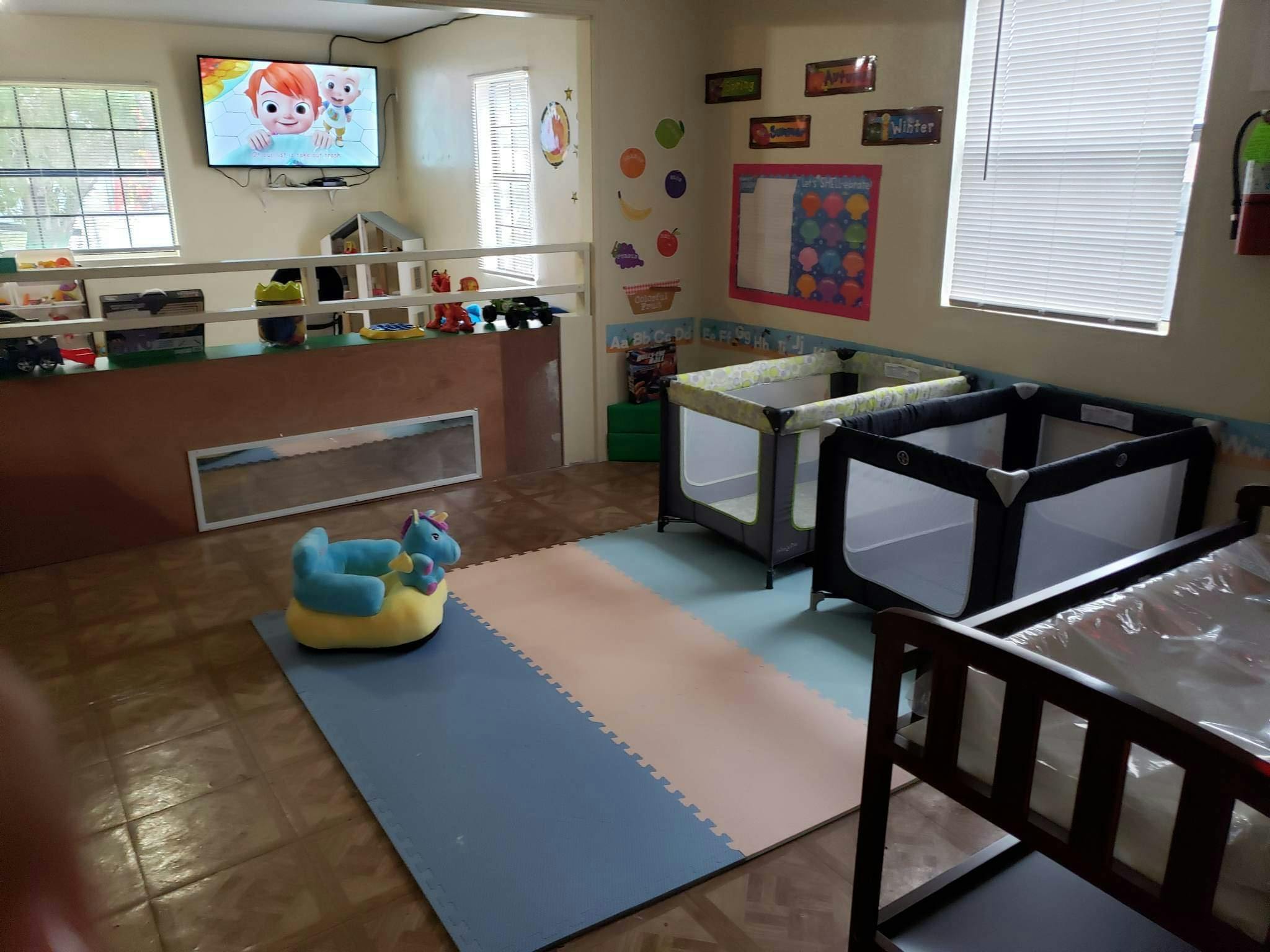 Playroom with cribs, playpen, and television showing a TV playing a cartoon