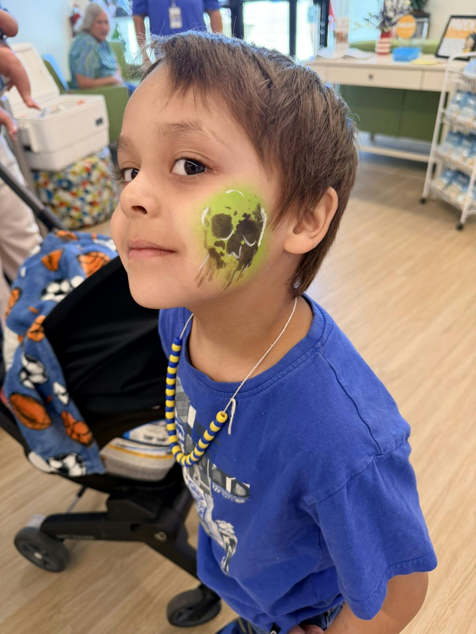 Child showing a painted green and black skull on their cheek