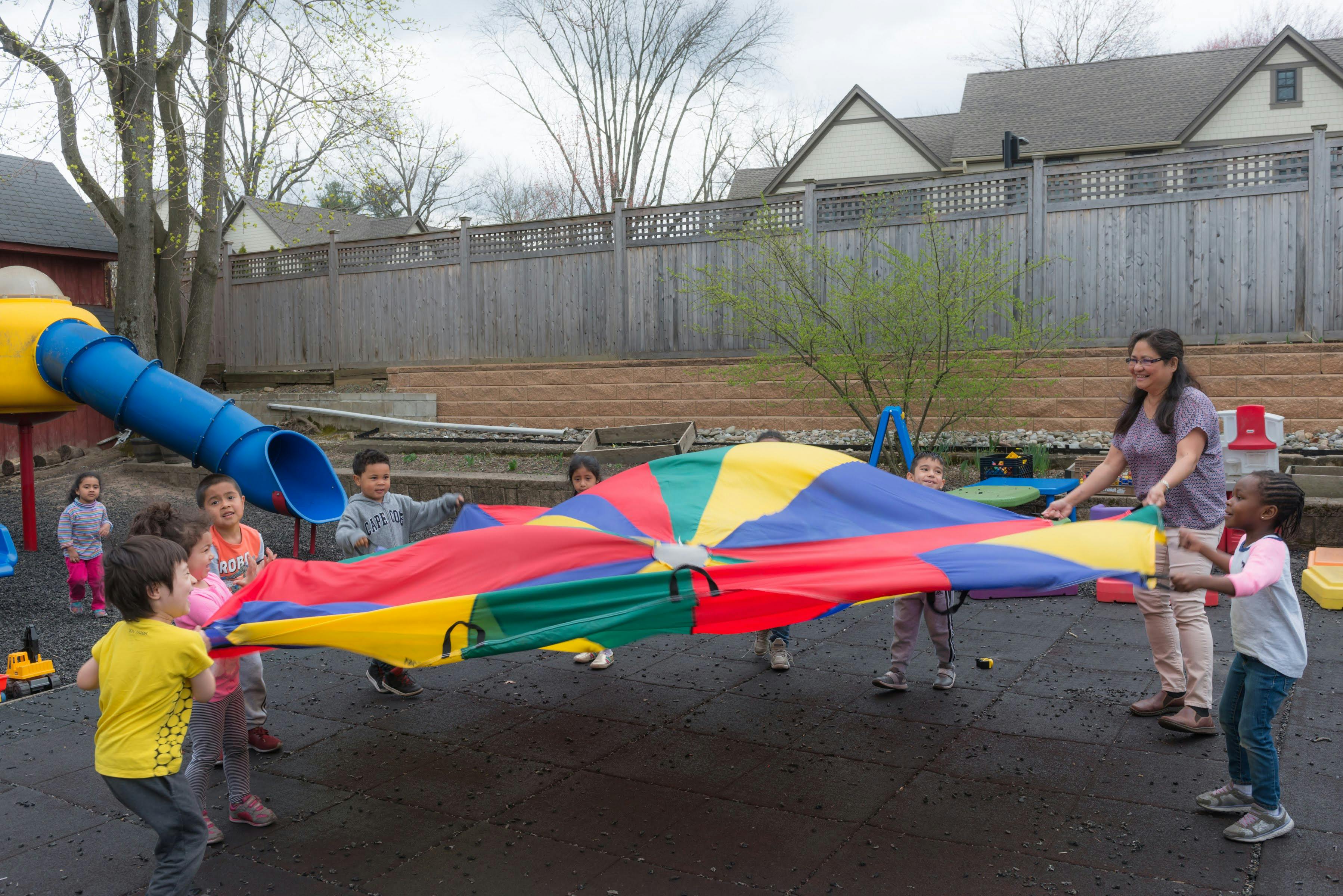 Adult and children playing with a colorful parachute outdoors