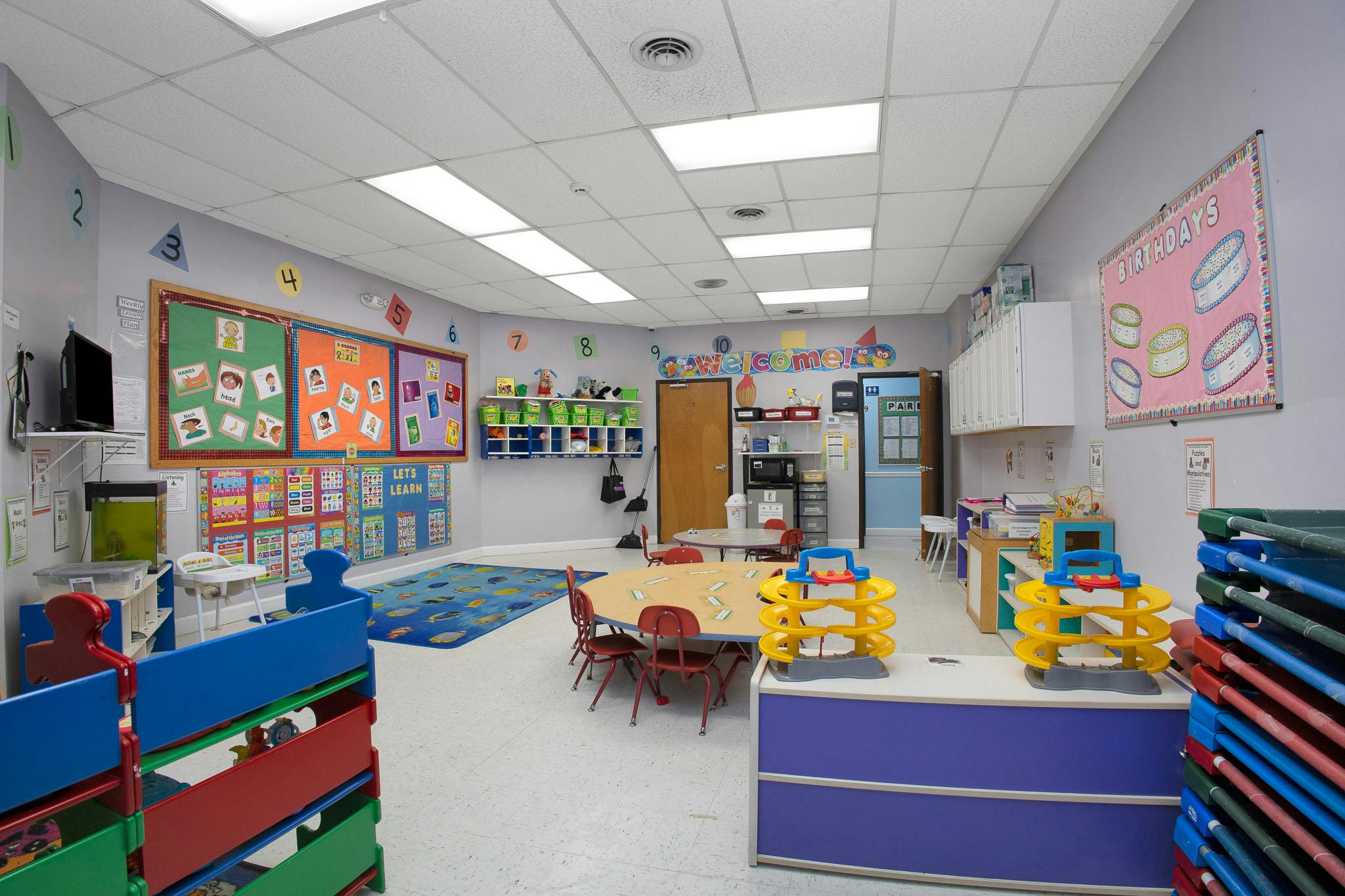 Classroom with educational posters, small tables and chairs, and play equipment