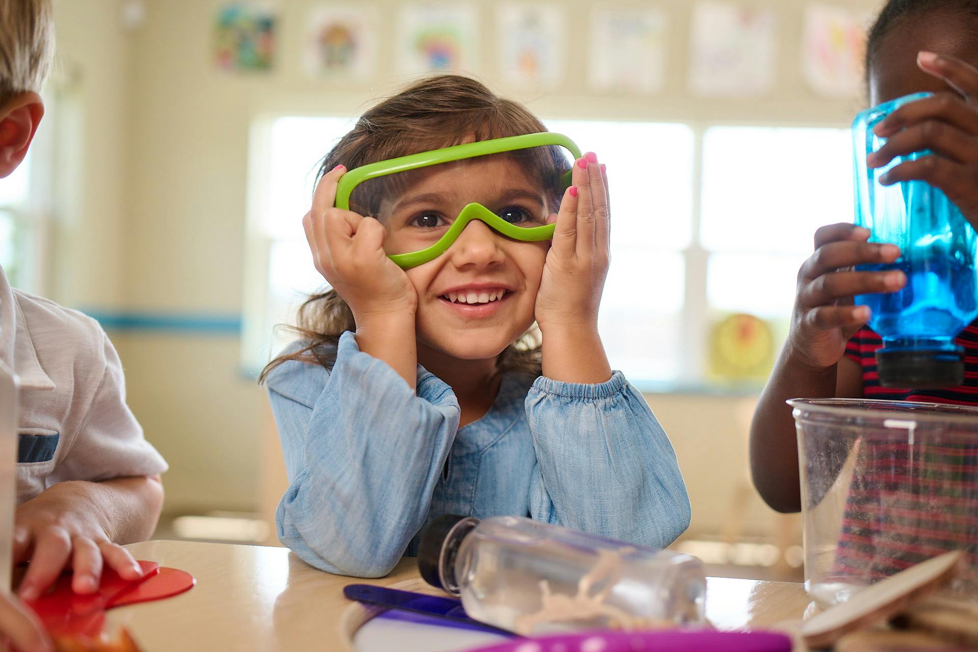 Child wearing green safety goggles in a classroom