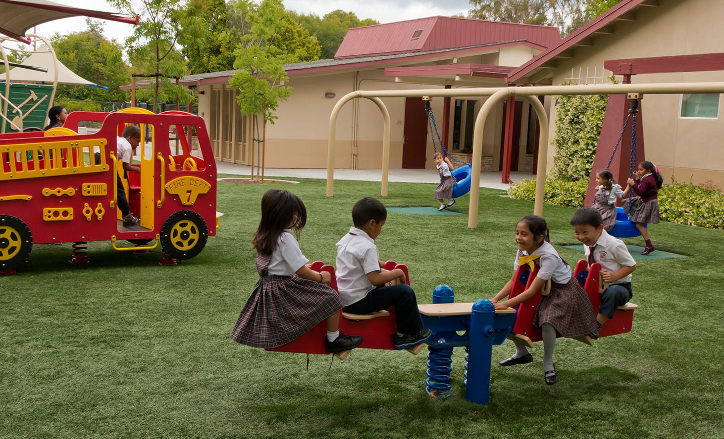 Children playing on a seesaw and fire truck in a playground