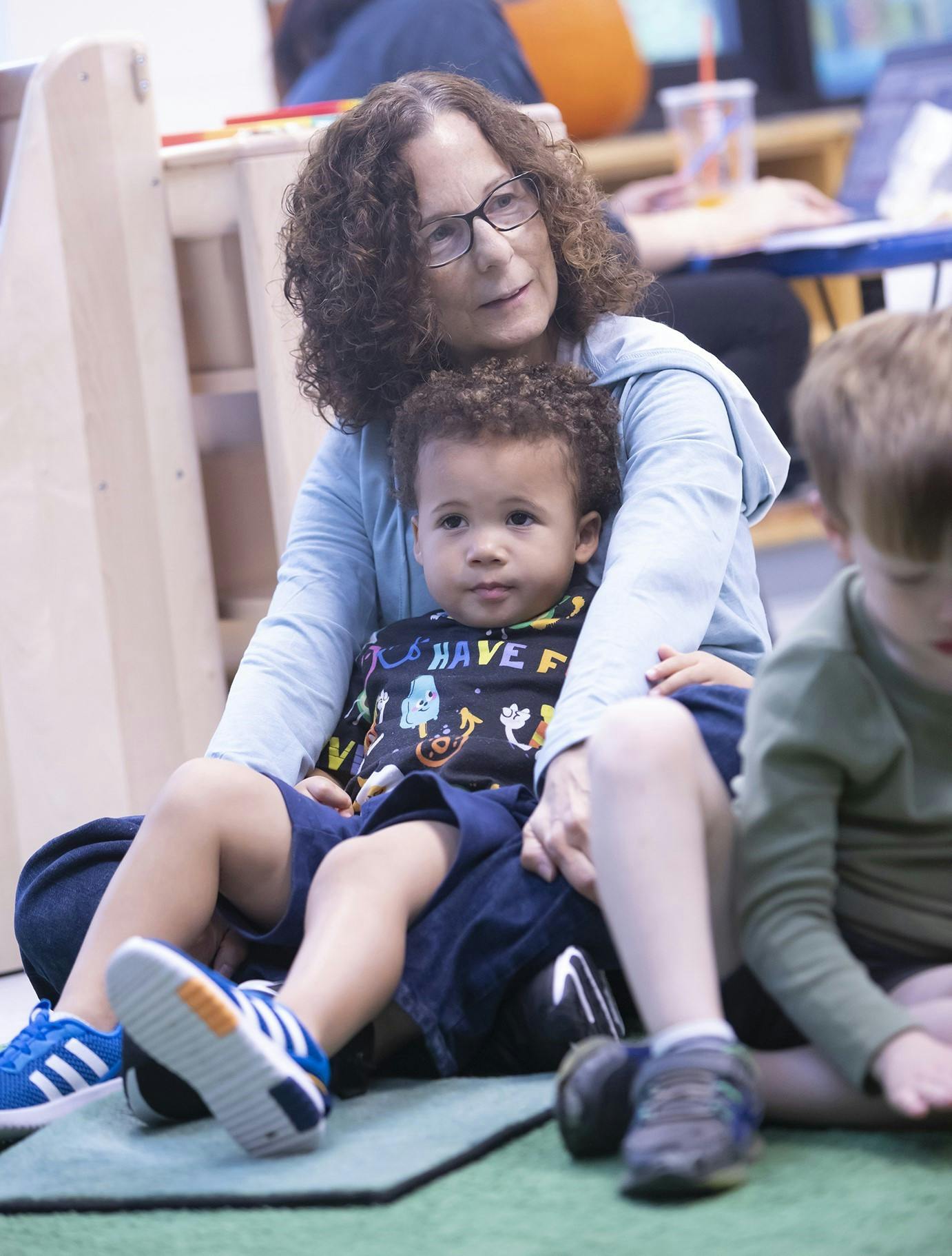 Person with glasses holding a child on their lap