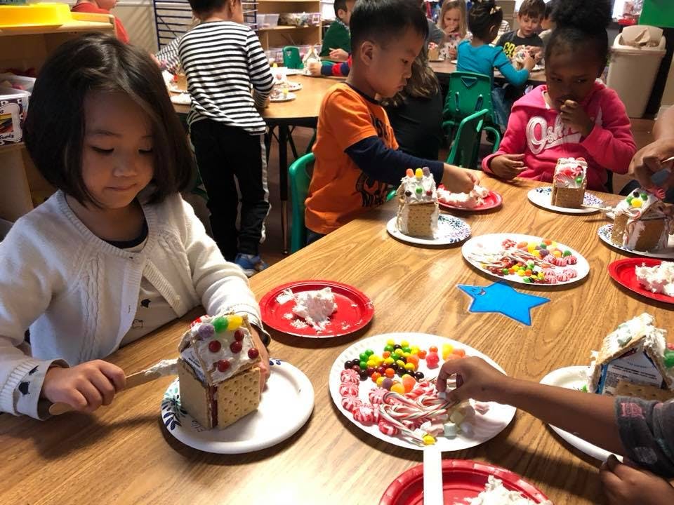 Children decorating gingerbread houses at a table