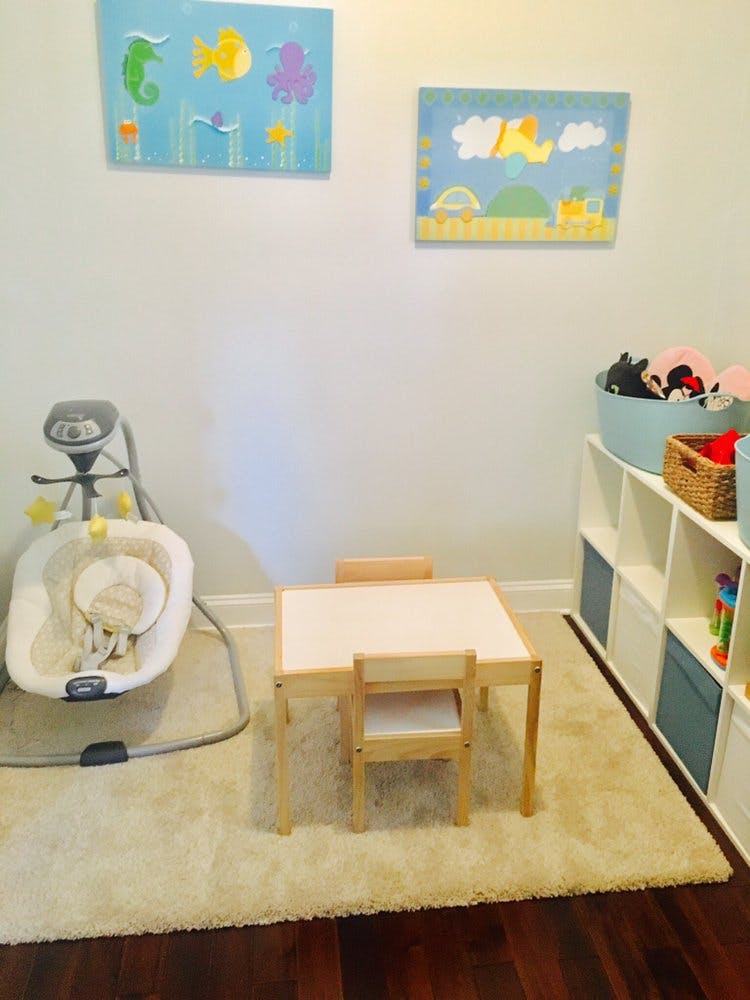 Baby swing, child's table and chairs, and storage shelves in a room