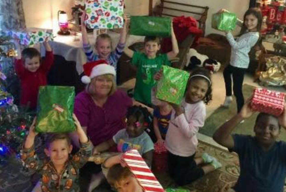 Adult and children holding up wrapped gifts