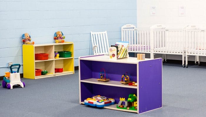 Playroom with shelves of toys and cribs