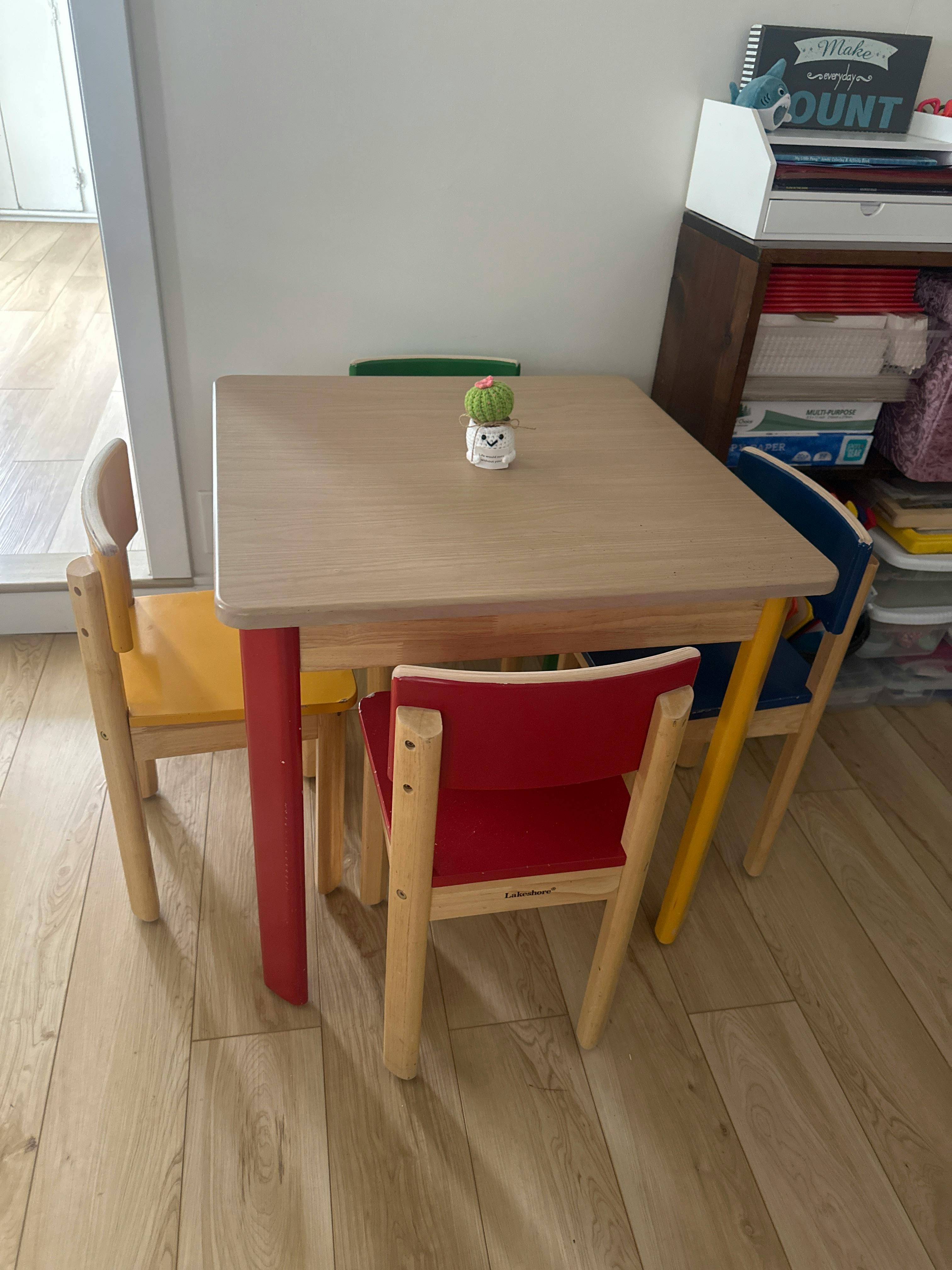 Small wooden table and chairs with red and blue accents on a wooden floor