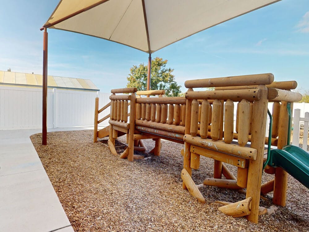Wooden playground with a green slide over woodchips