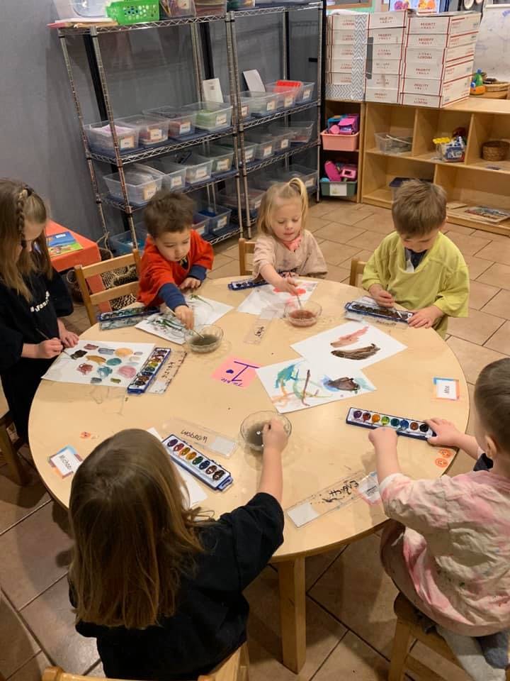 Children painting at a round table in a classroom
