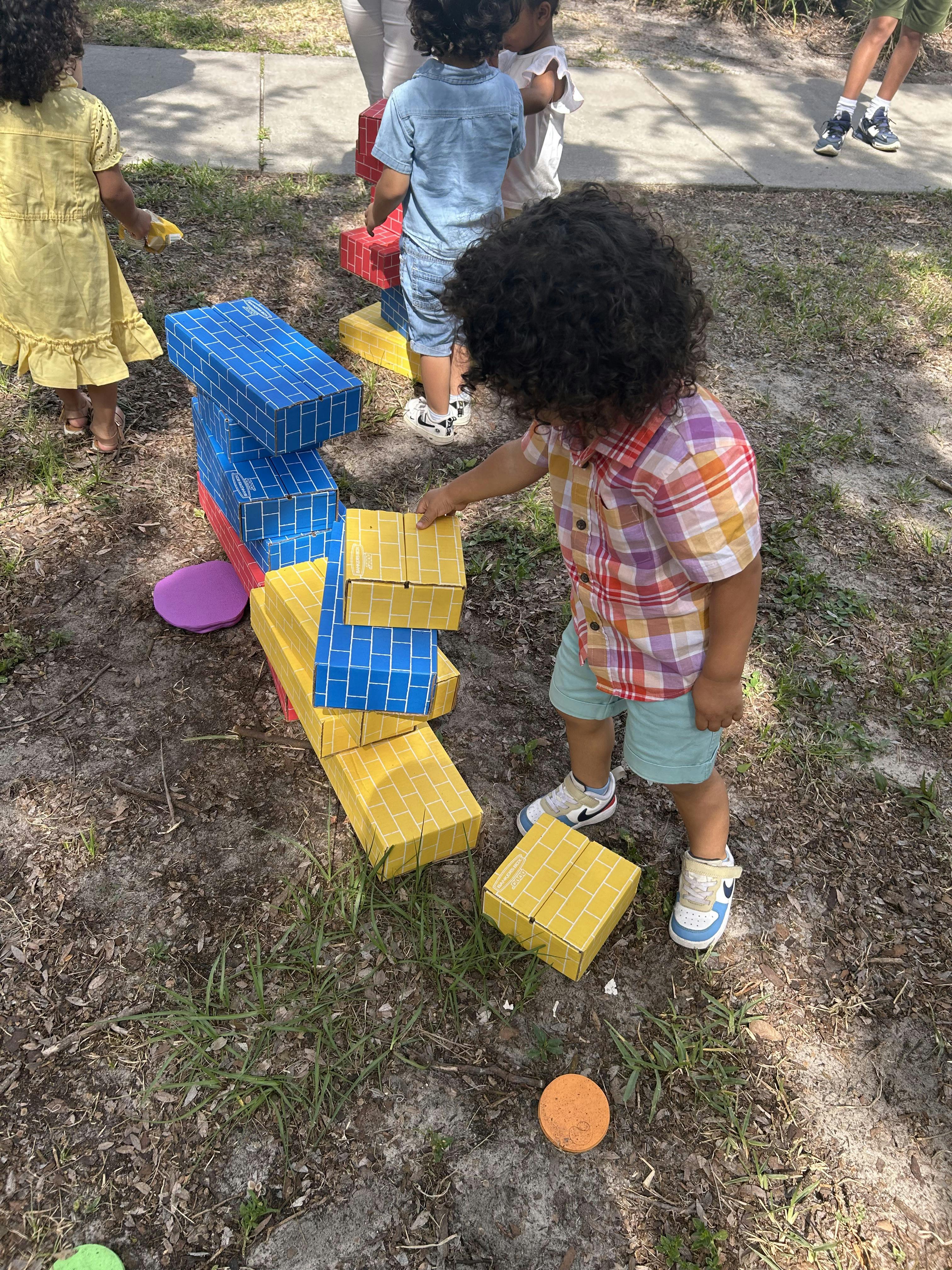 Children playing with large cardboard blocks outdoors