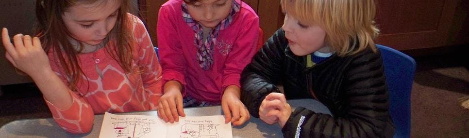 Three children looking at a paper