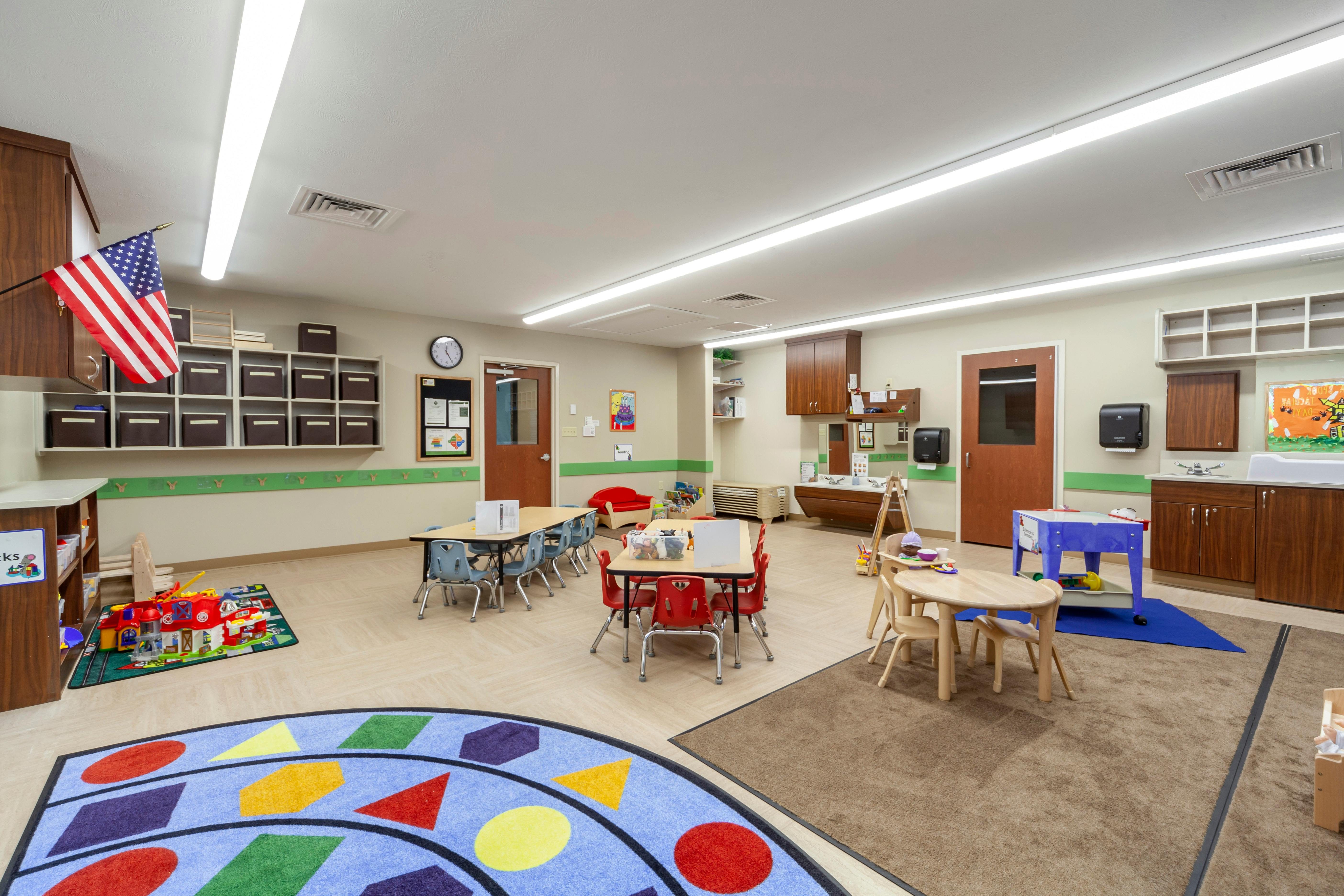 A colorful children's classroom with small tables, chairs, and play areas