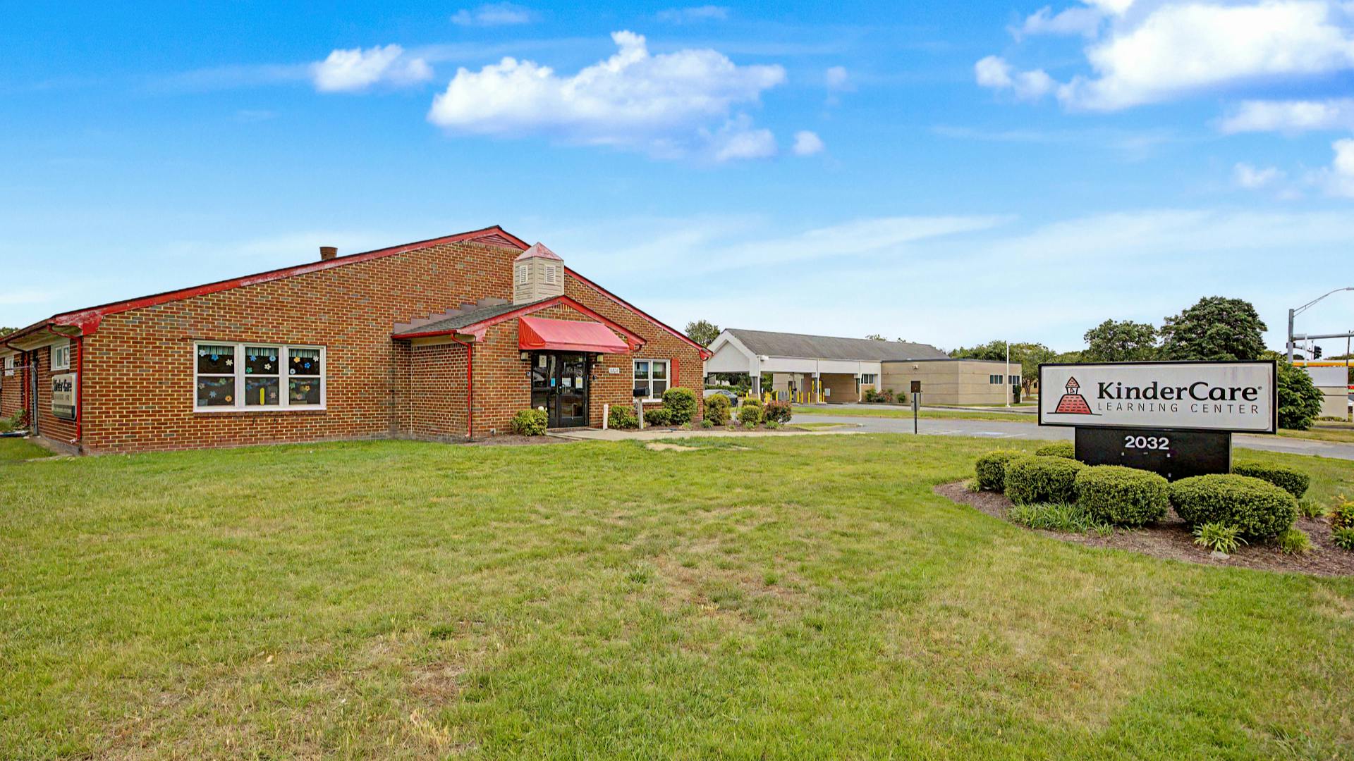 Brick building with red roof and awning, KinderCare Learning Center sign