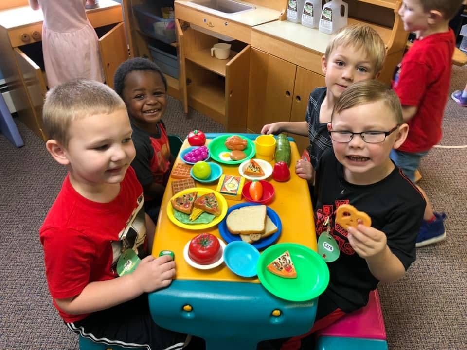 Children playing with toy food at a table