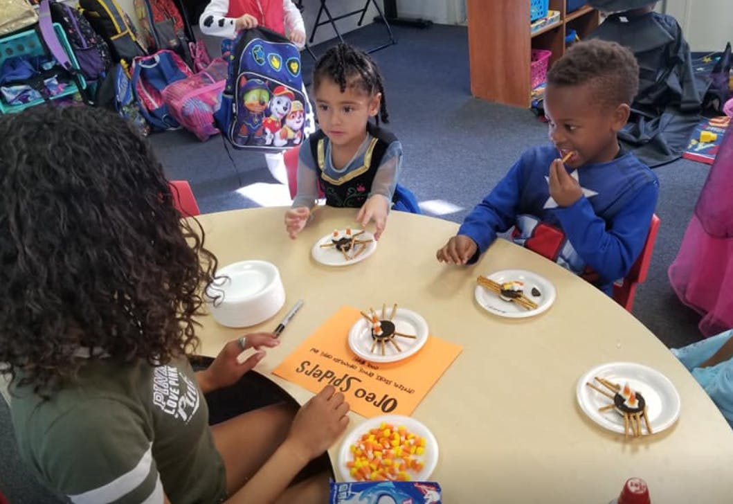 Person and two children making spider crafts at a table