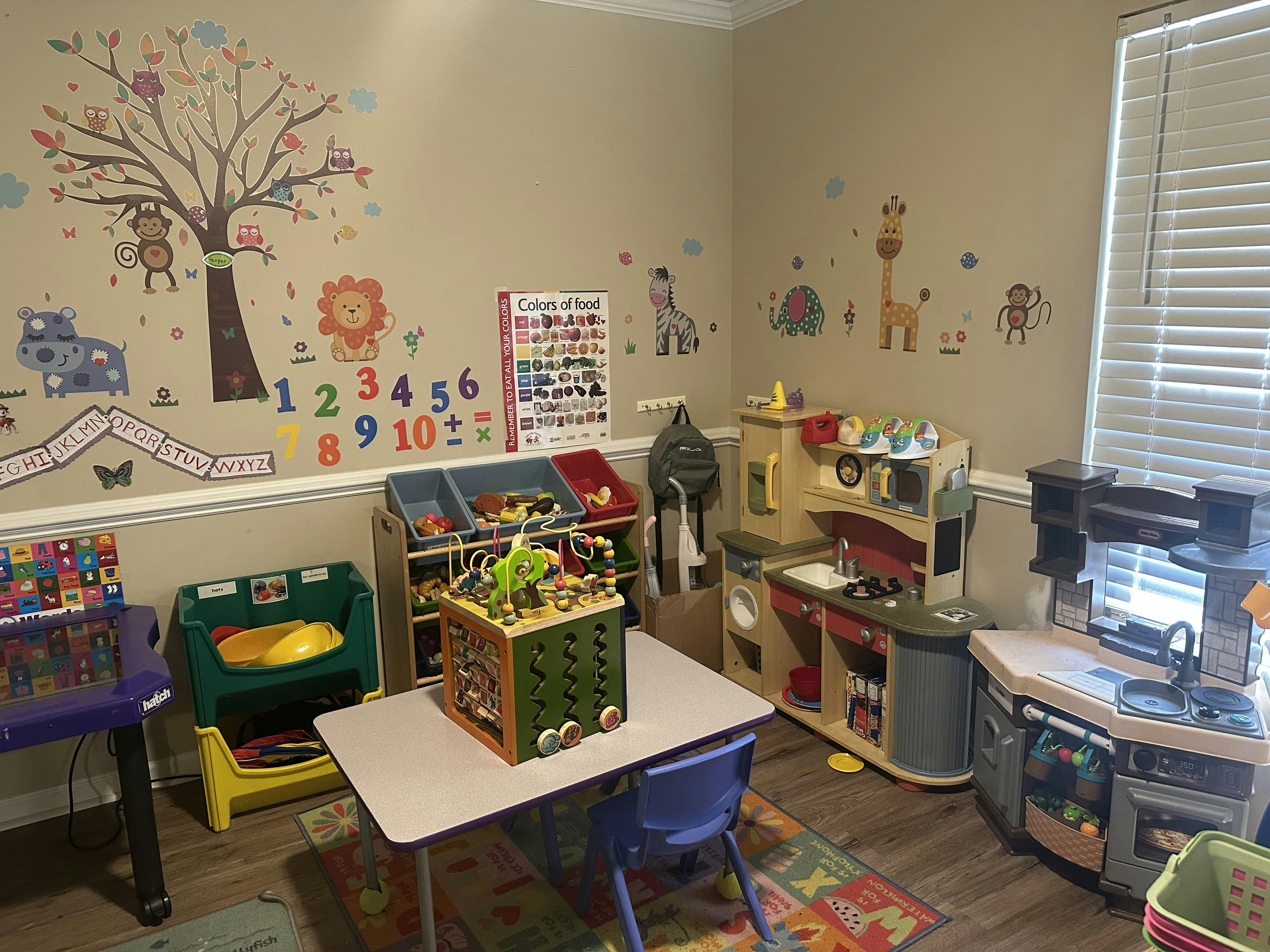 Playroom with wall decals, toy kitchen, and activity cube on a table