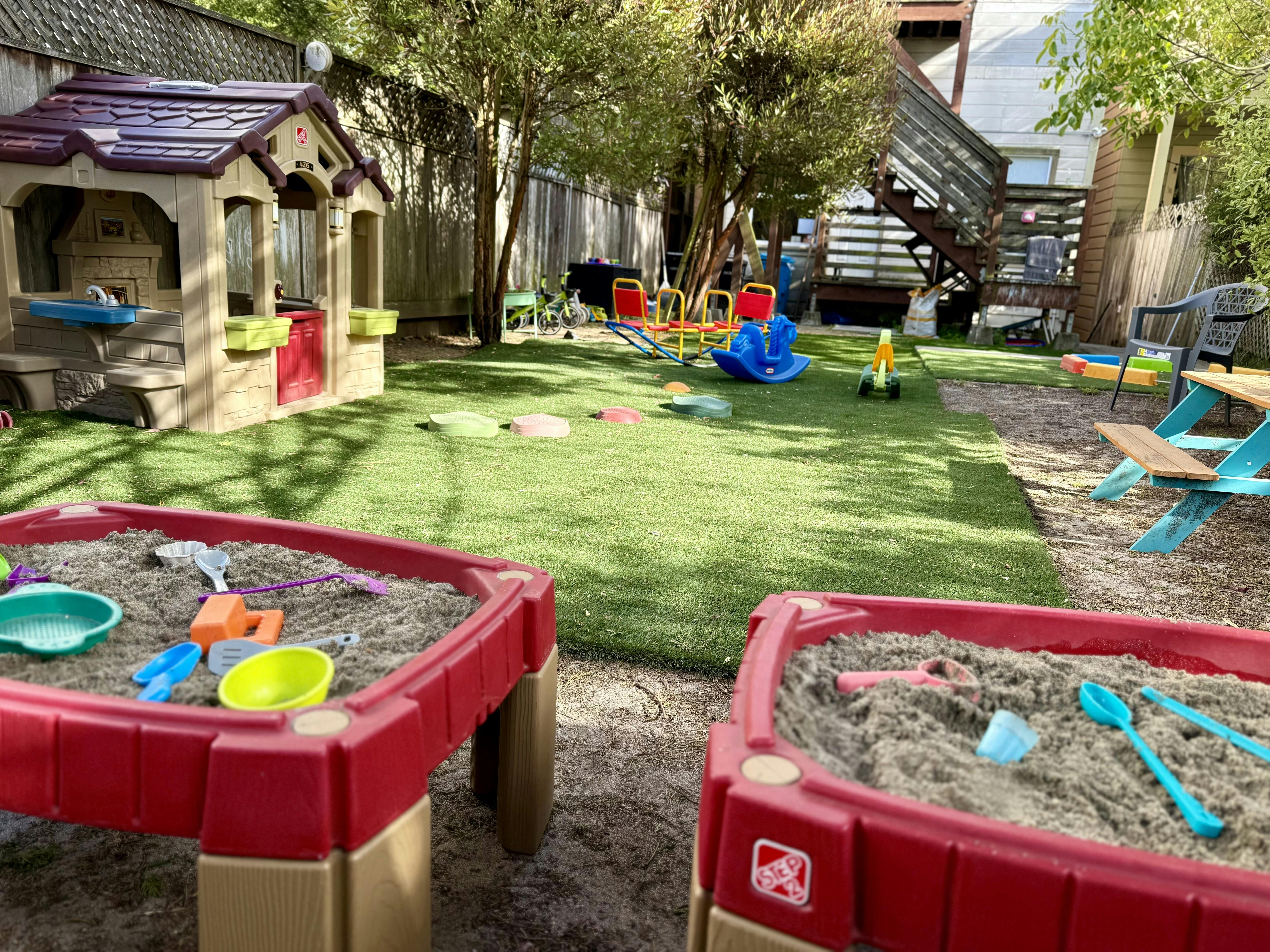 Two red sandboxes with toys in a backyard playground