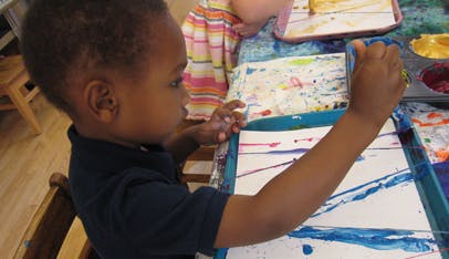 Child painting on paper with blue paint