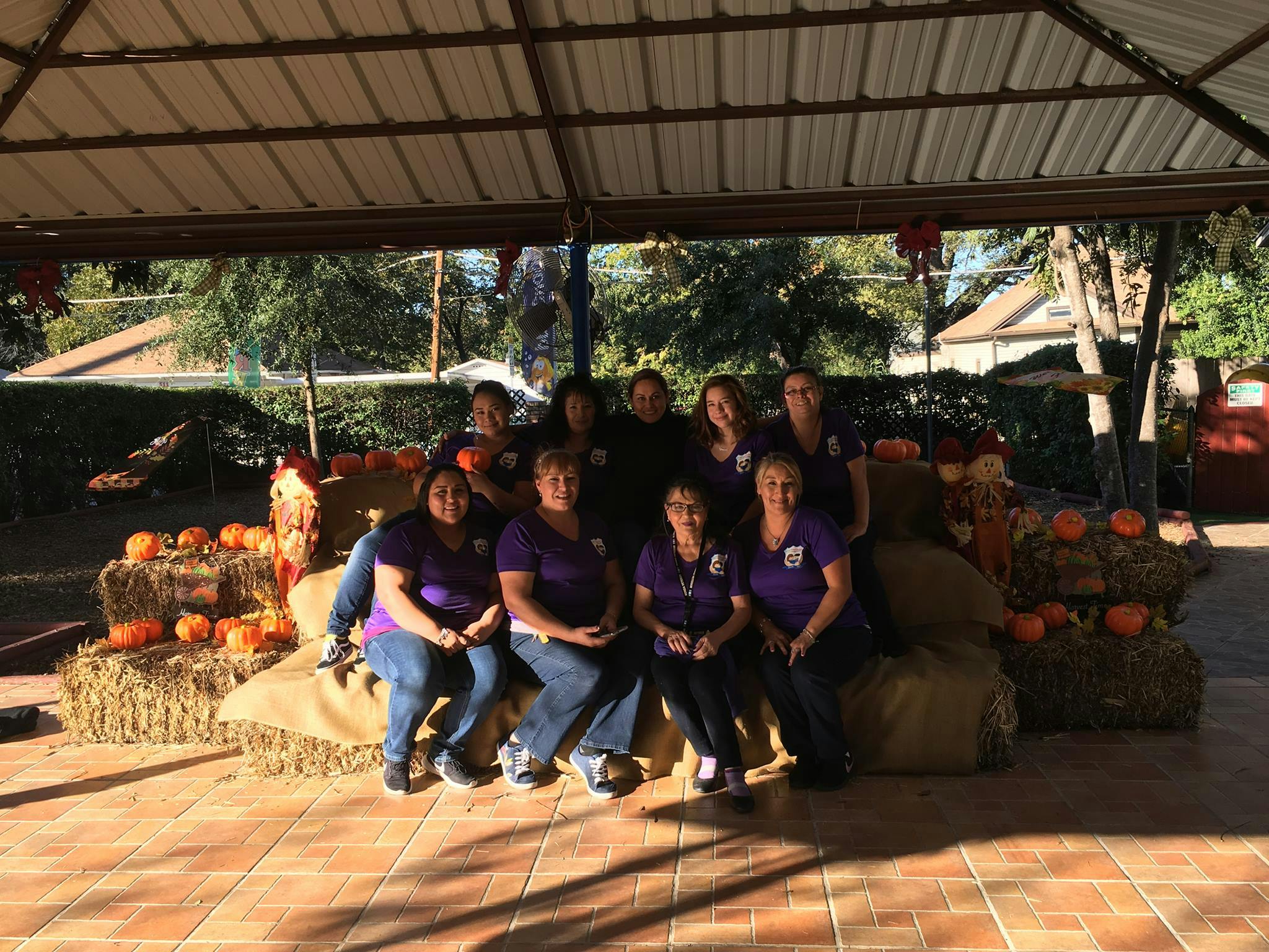 Group of people sitting on hay bales with pumpkins