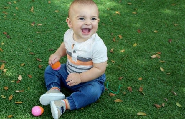 Child sitting on grass with two small balls
