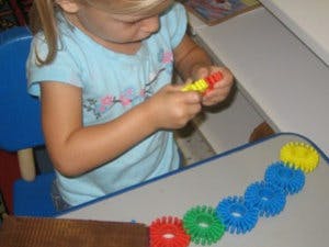 Child playing with colorful interlocking toys at a table
