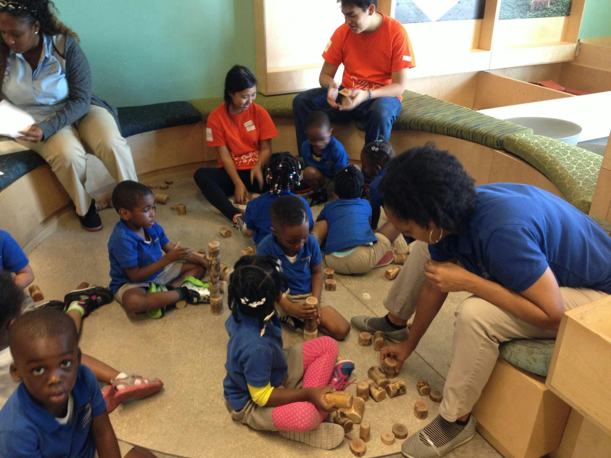 Adults and children playing with wooden blocks on the floor