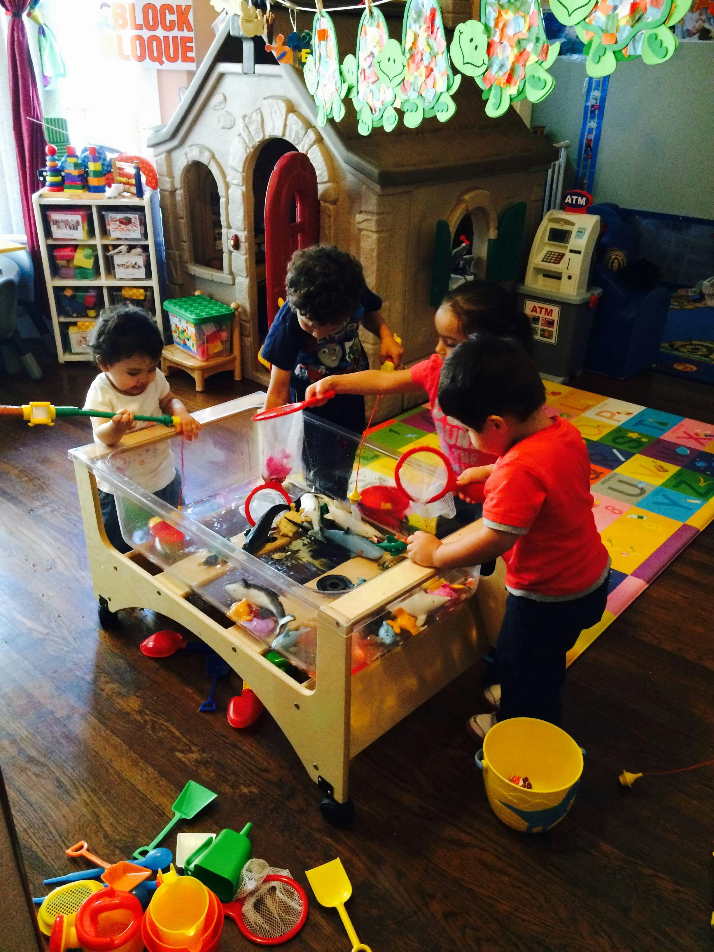 Children playing at a water table with toys