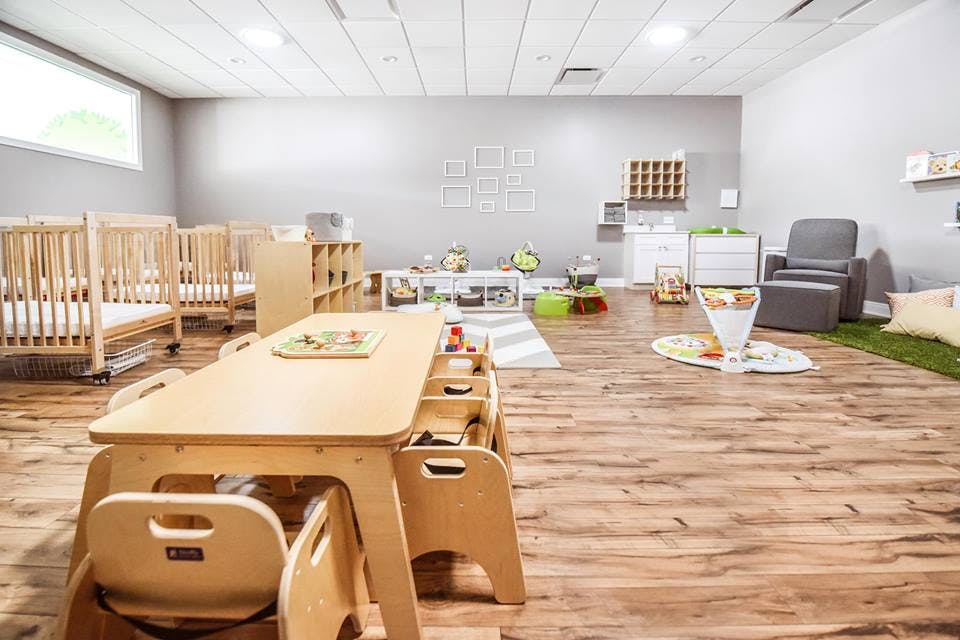 Empty classroom with cribs, tables, and chairs