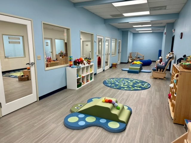 Hallway with multiple doors and windows looking into rooms, play mats on floor