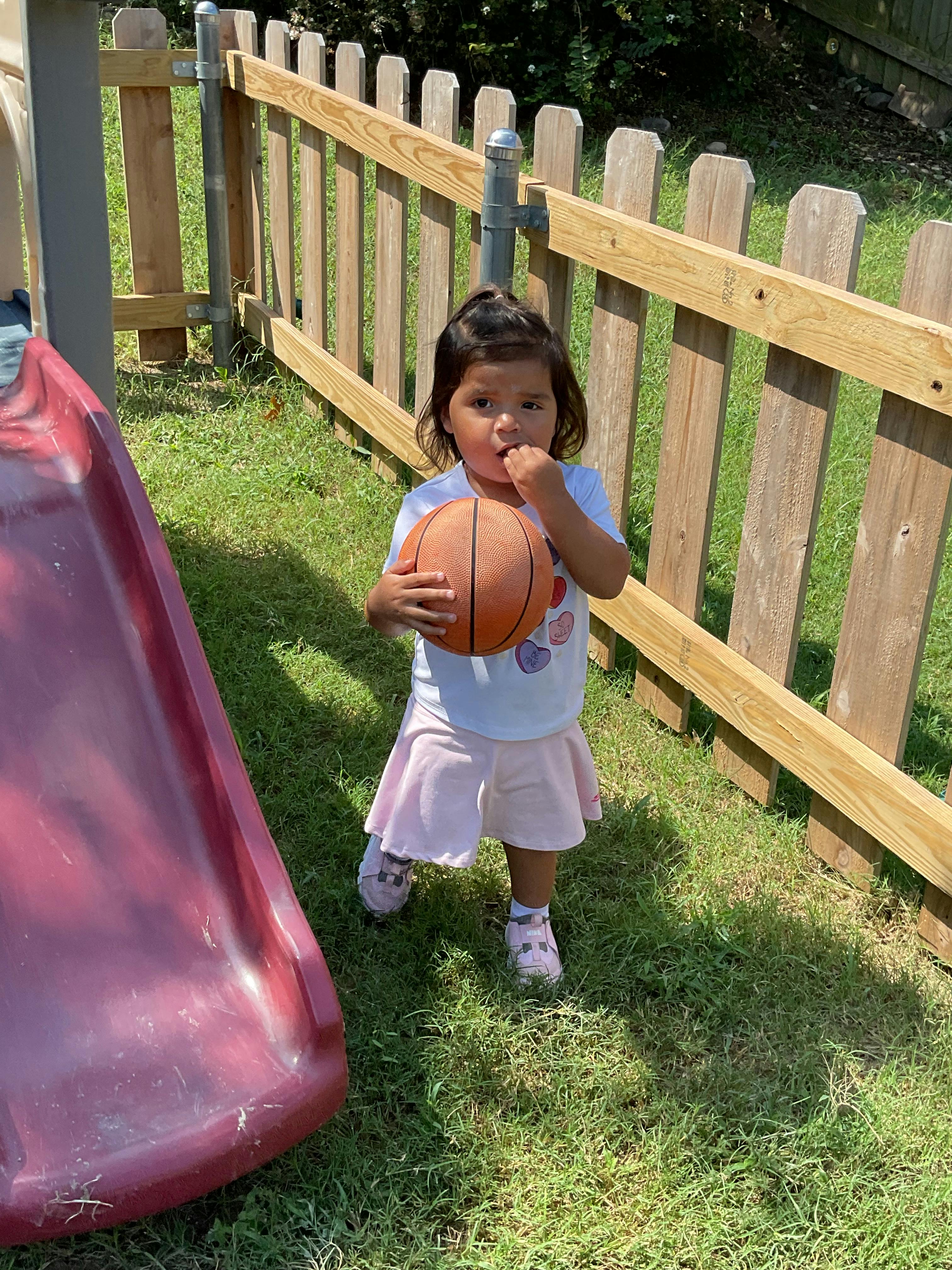 Child holding a basketball outdoors