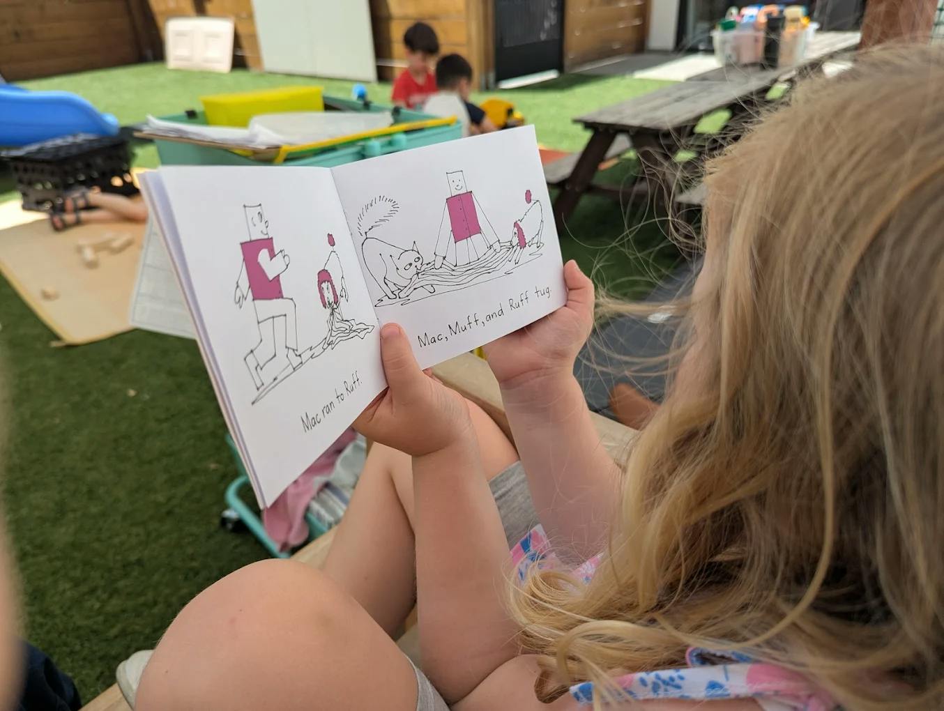 Child reading an illustrated book outdoors