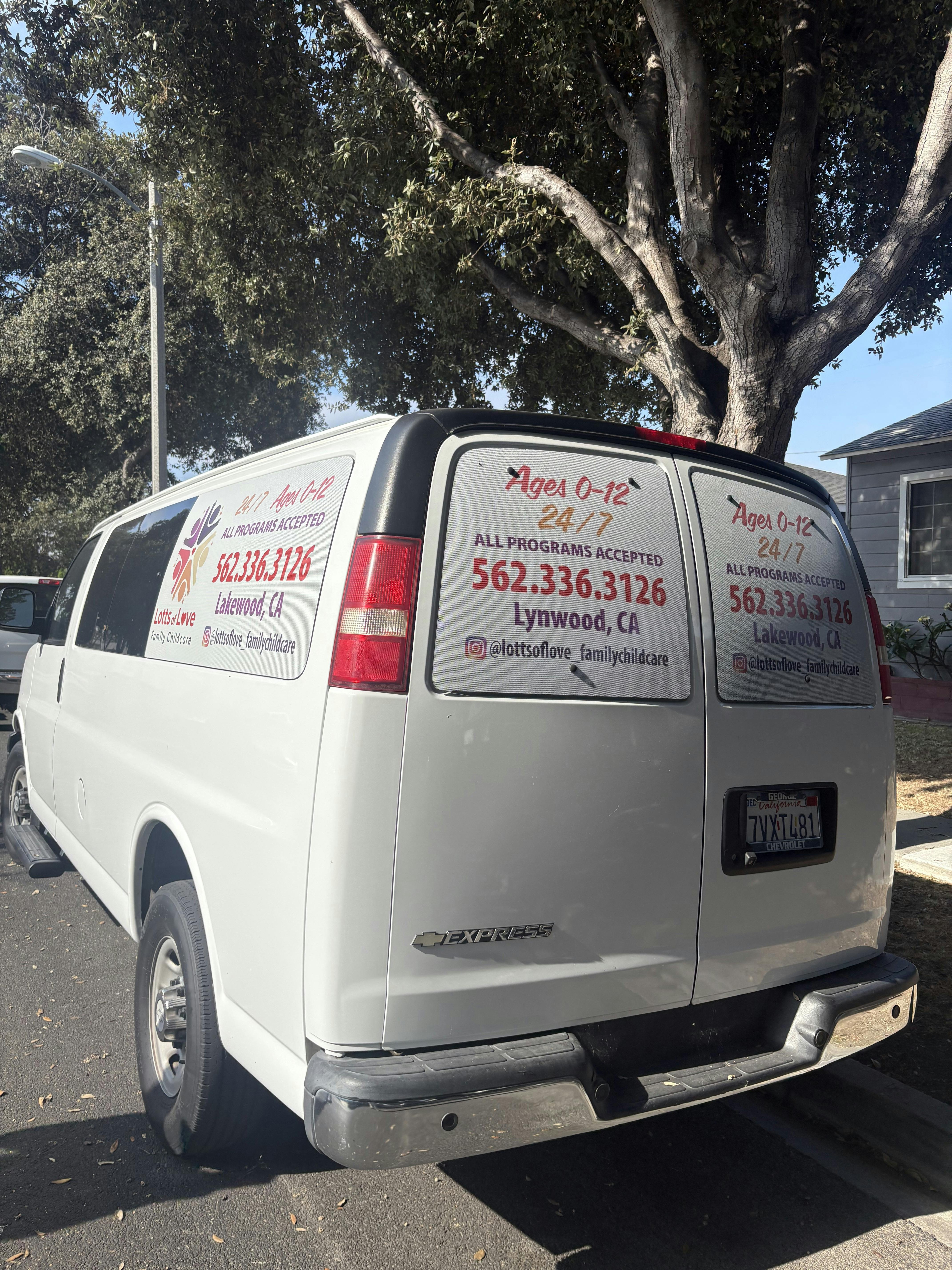 White childcare service van with contact information printed on the windows