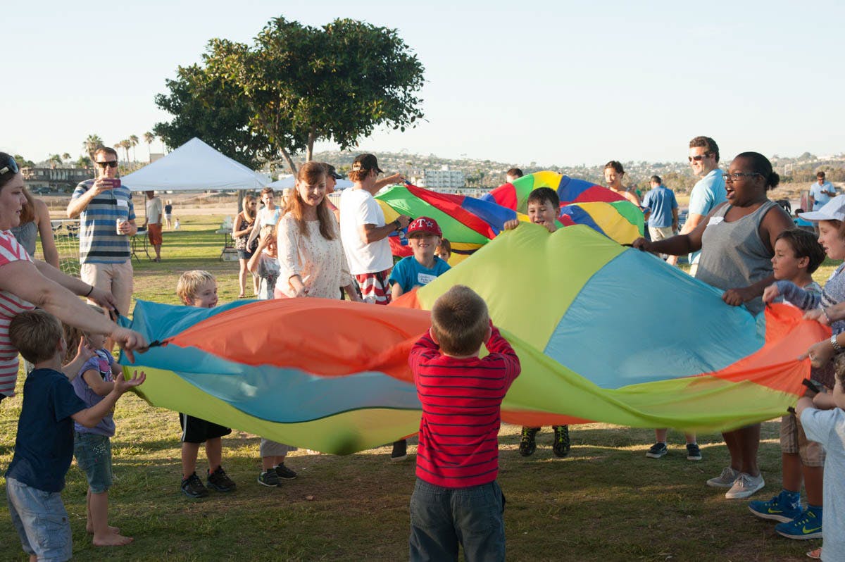 Adults and children playing with a large colorful parachute outdoors