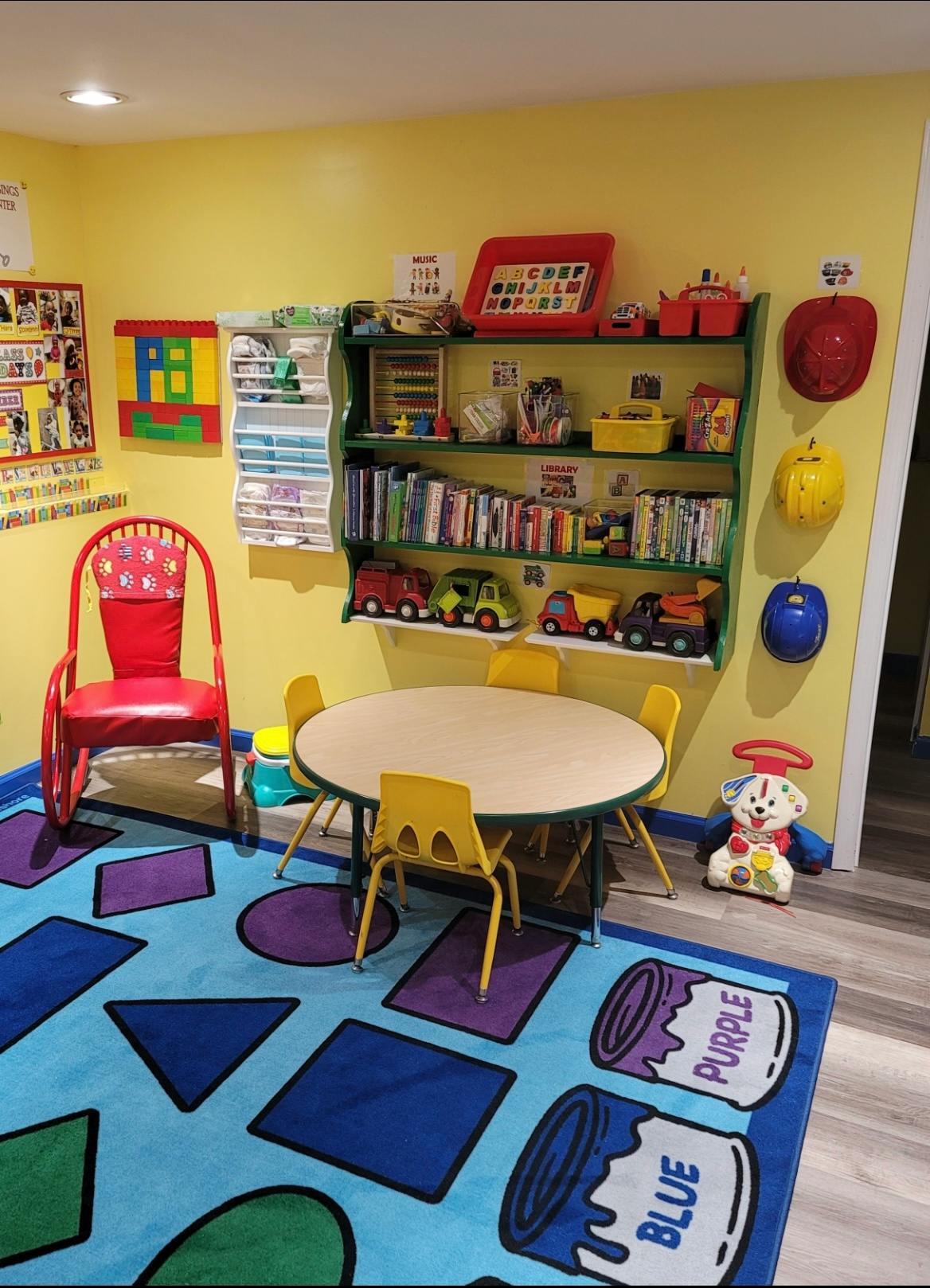 Children's classroom with small table and chairs, shelves with books and toys