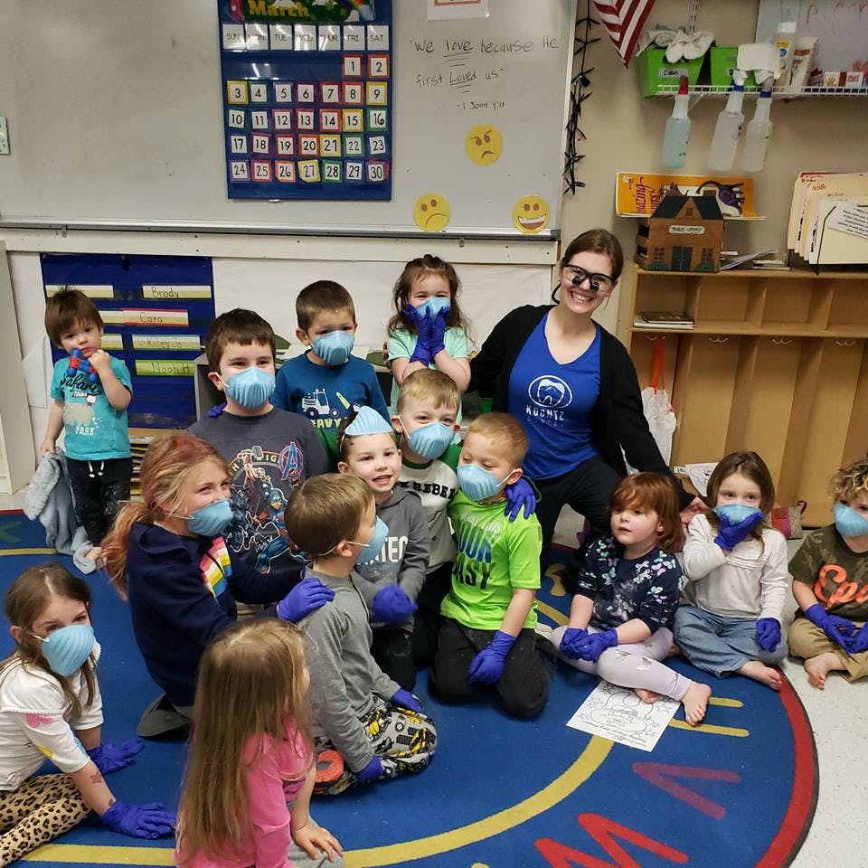 Adult and children wearing masks and gloves in a classroom