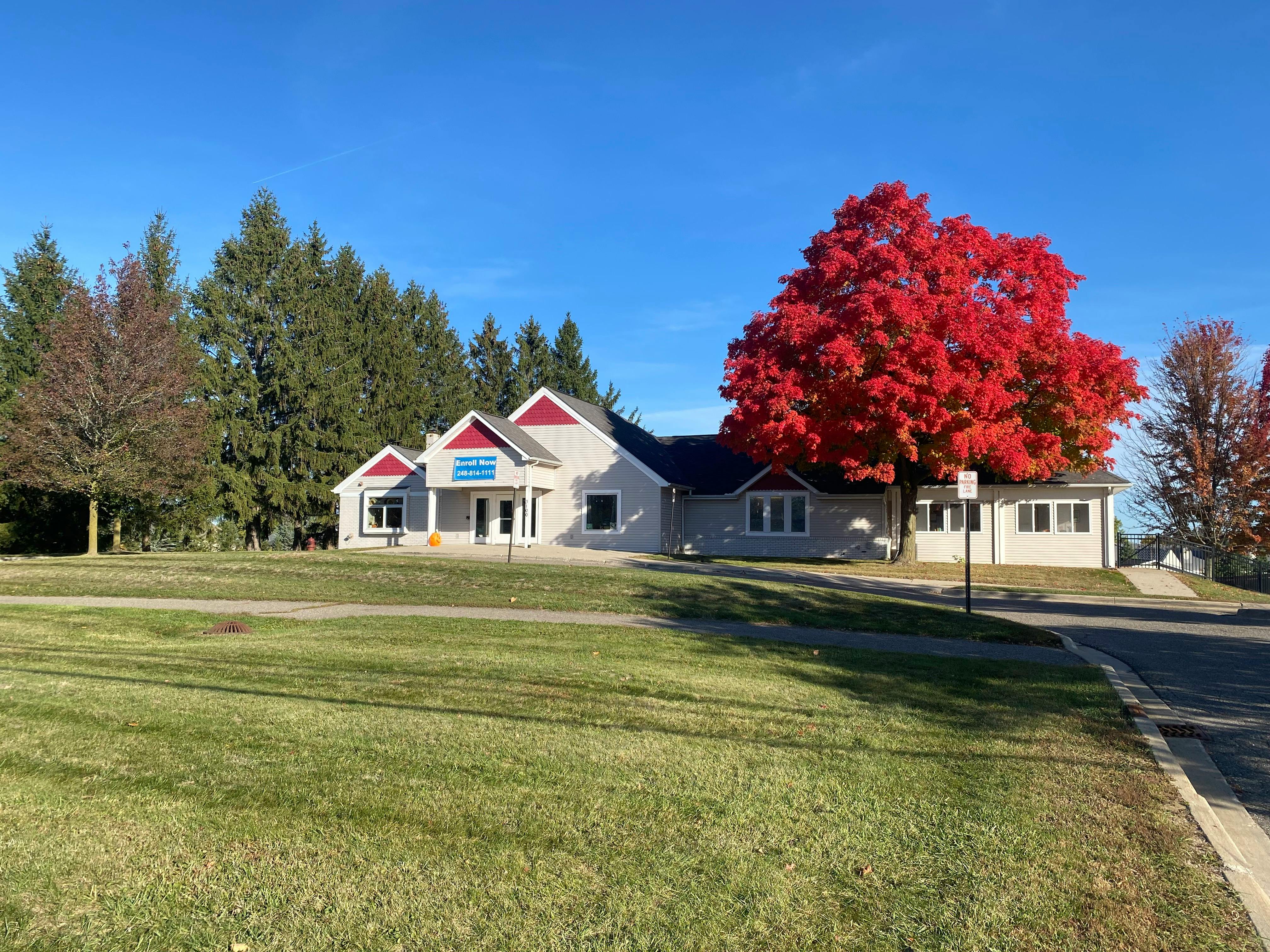 Building with red roof and a large tree with red leaves