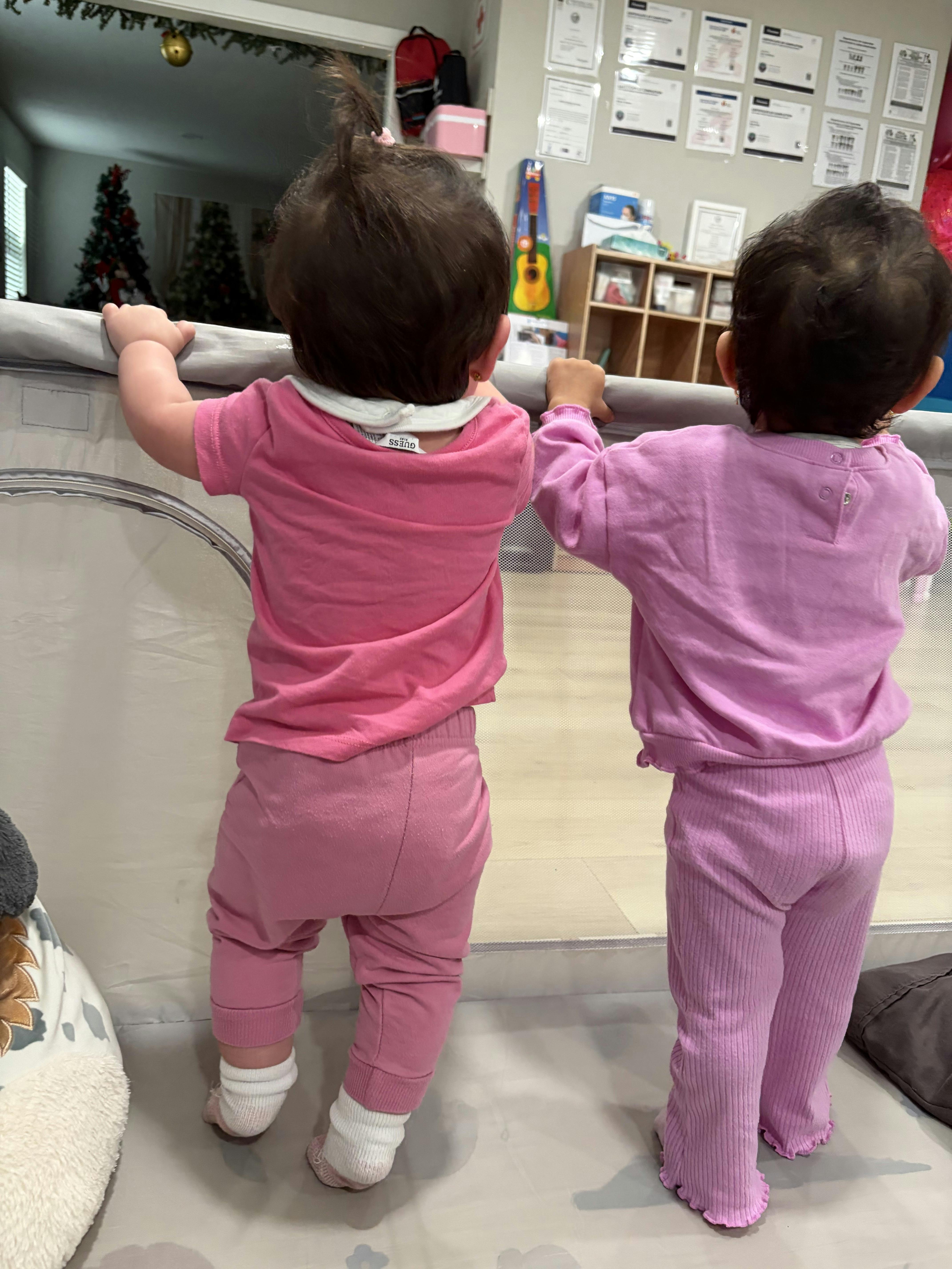 Two children standing and holding onto a barrier