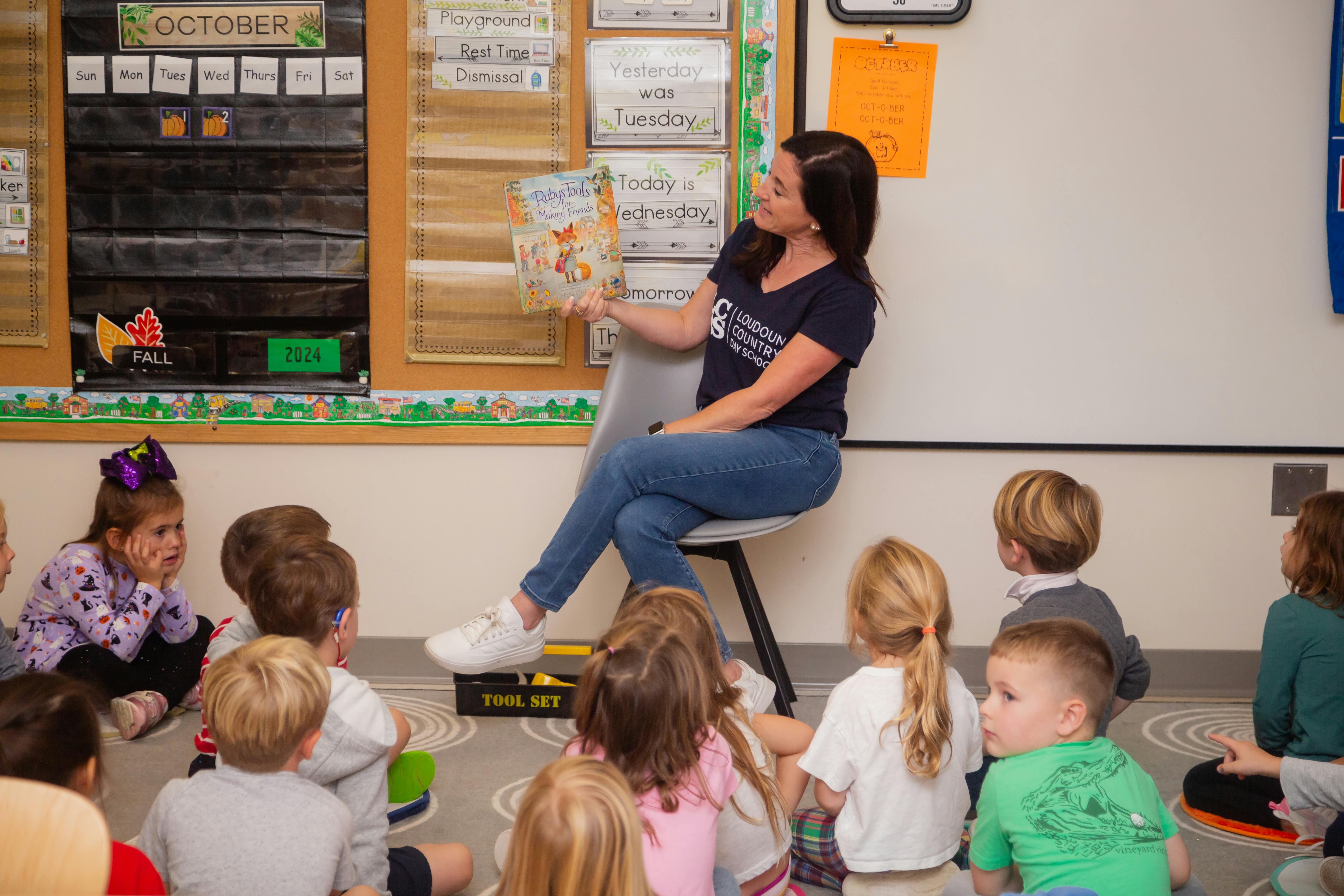 Teacher reading a book to a group of children in a classroom