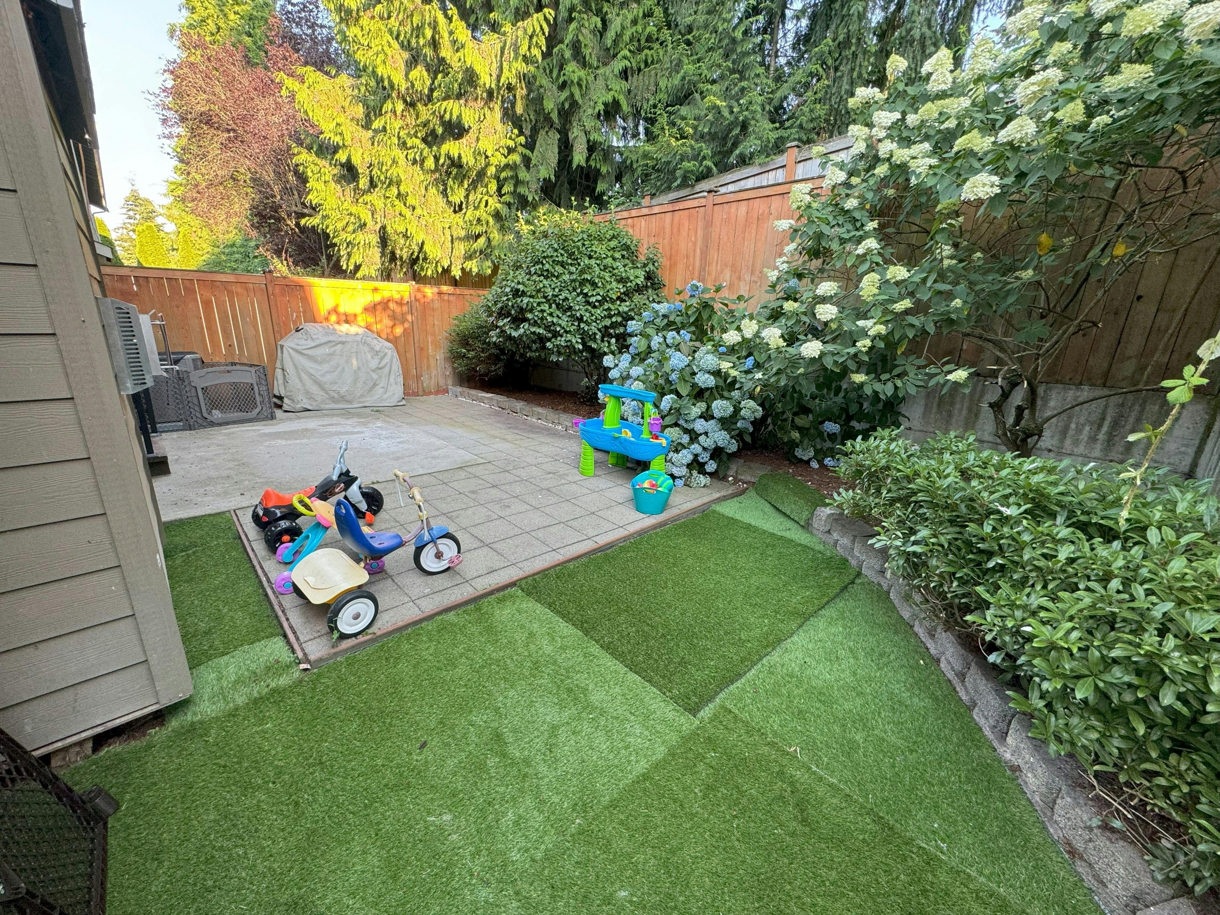 Backyard patio with artificial turf and children's toys
