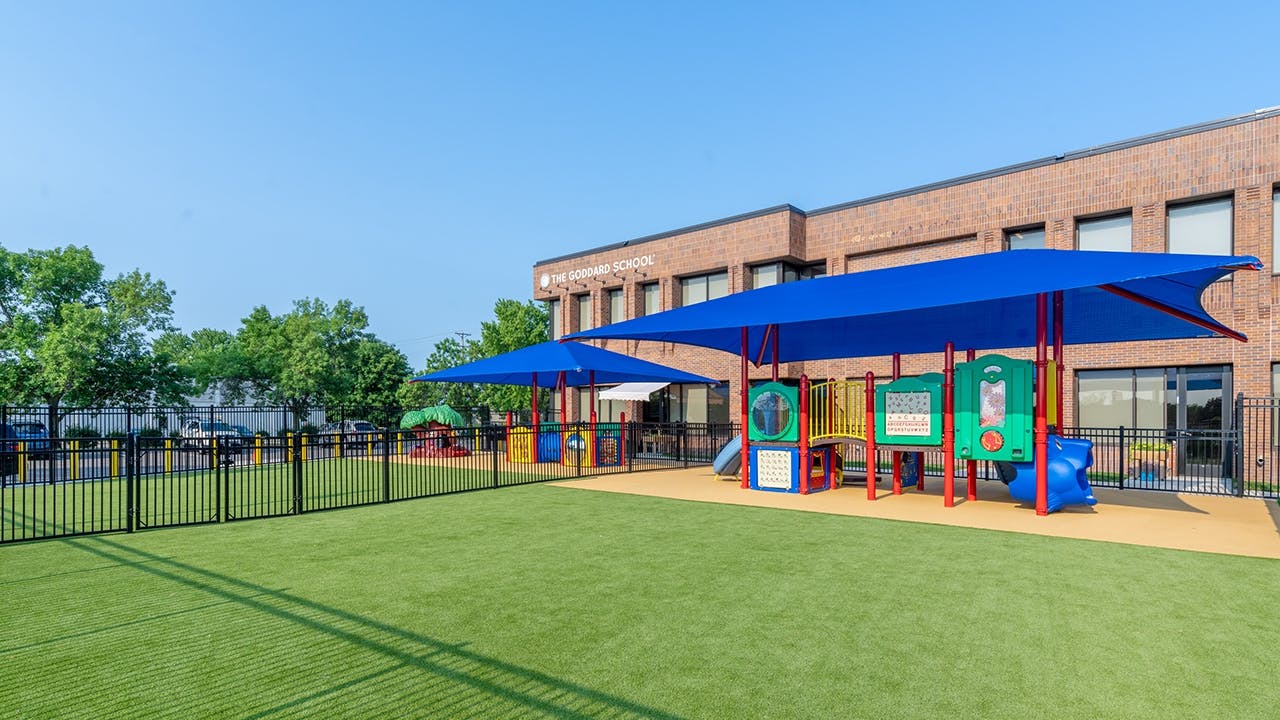Playground with blue shade structures and a brick building